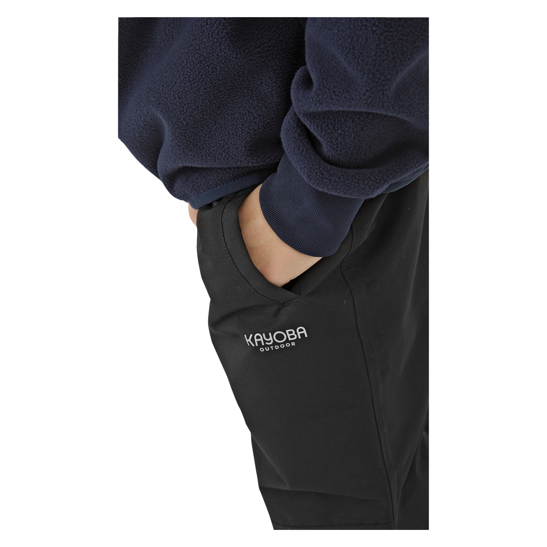 Eine Person in einem marineblauen Fleeceoberteil steckt ihre Hand in die Tasche der schwarzen Kayoba Outdoor Kinderhose, auf deren Oberschenkel "KAYOBA OUTDOOR" in Weiß aufgedruckt ist.