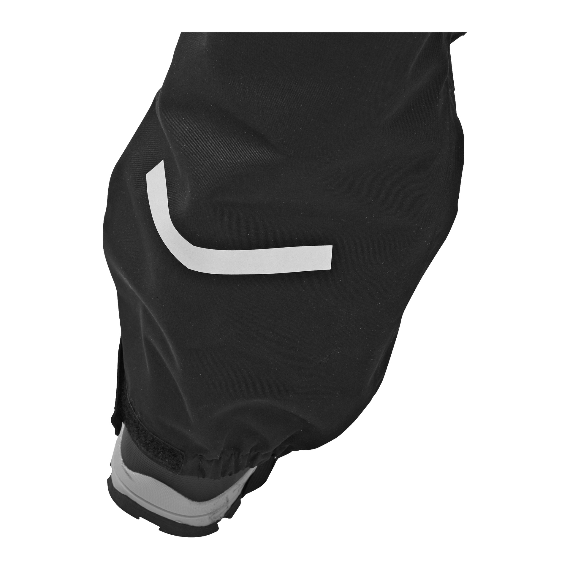 Nahaufnahme des unteren Abschnitts der schwarzen Kayoba Outdoor Kinderhose, die einen weißen reflektierenden Streifen und einen Teil eines grau-schwarzen Schuhs am Boden zeigt.
