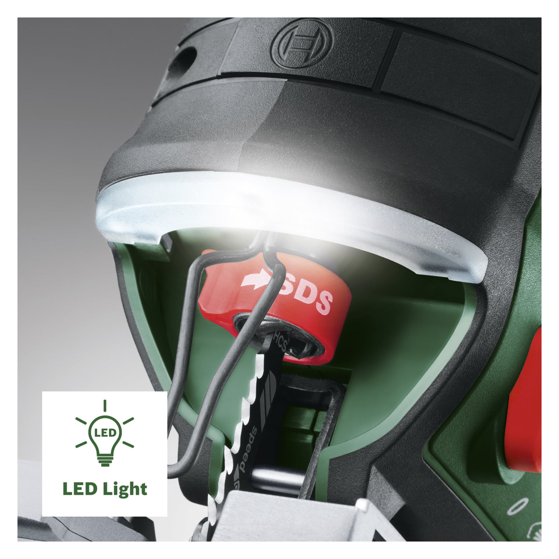 Bosch Power 4 All AdvancedSaw 18V-140 batteripuslespillet vises i nærbilde, og fremhever et opplyst LED-lys over arbeidsområdet. Verktøyets design inkluderer et karakteristisk rødt SDS-element og et eksponert blad i det grønne og svarte hylstret. Et LED-lysikon og en etikett vises nederst til venstre.
