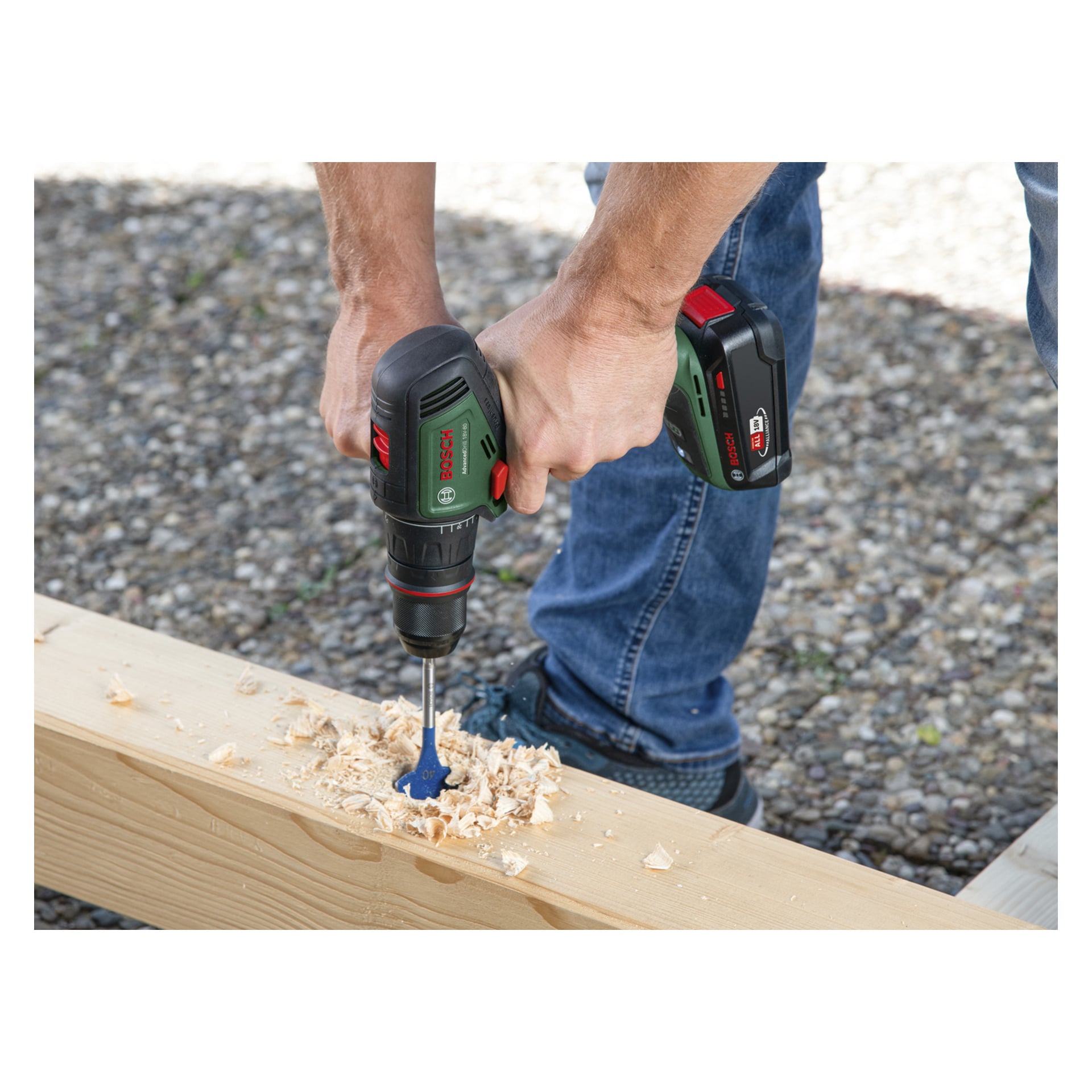 Sinisiin farkkuihin pukeutunut henkilö poraa reikää puulautaan Bosch Power 4 All Brushless AdvancedDrill 18V-80 ruuvimeisselillä, kun puulastut kerääntyvät poranterän lähelle.