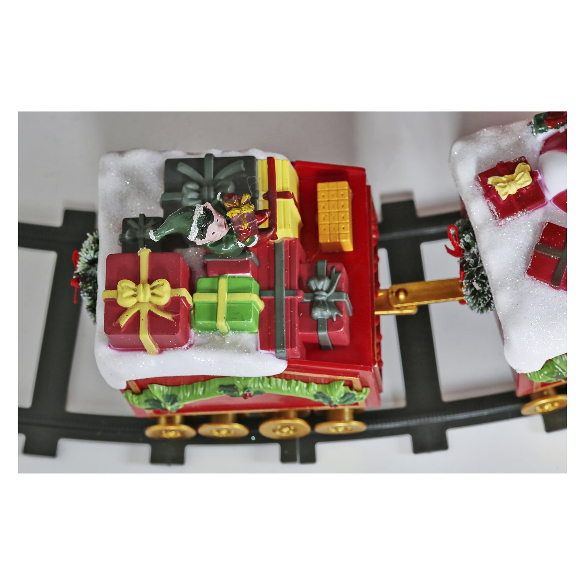 Ein festlicher EKVIP-Weihnachtszug präsentiert einen Spielzeugzugwagen, der mit schneeartigen Akzenten bedeckt ist und mit bunt verpackten Geschenken beladen ist, die mit gelben, grünen und roten Bändern verbunden sind. Eine fröhliche Elfenfigur mit Geschenken ist ebenfalls an Bord, und der Zug steht auf schwarzen Gleisen.