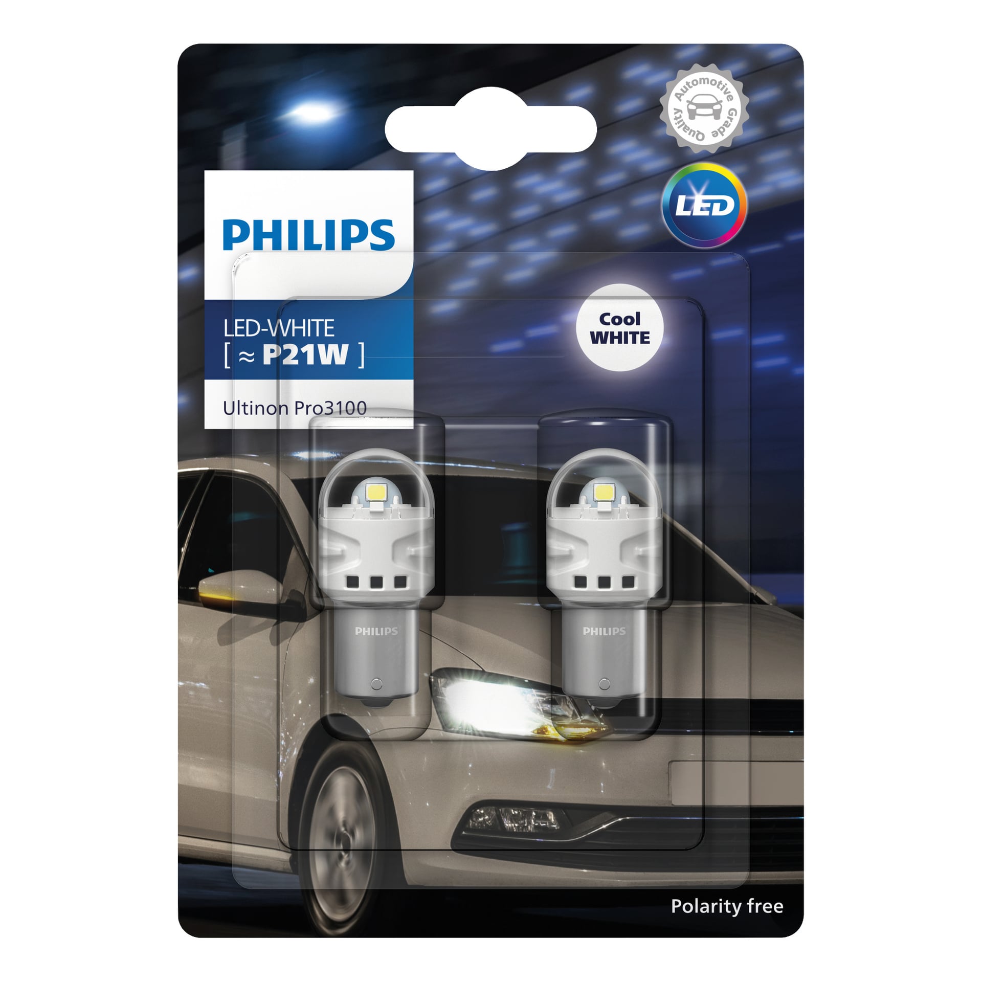 Philips Ultinon Pro3100 -ajovalopolttimot 2-pakettina näytettynä vähittäismyyntipakkauksessa, jossa kaksi polttimoa näkyvissä. Pakkauksessa korostetaan viileää valkoista valoa ja helppo napaisuusvapaa asennus, ja taustalla näkyy valkoinen auto.