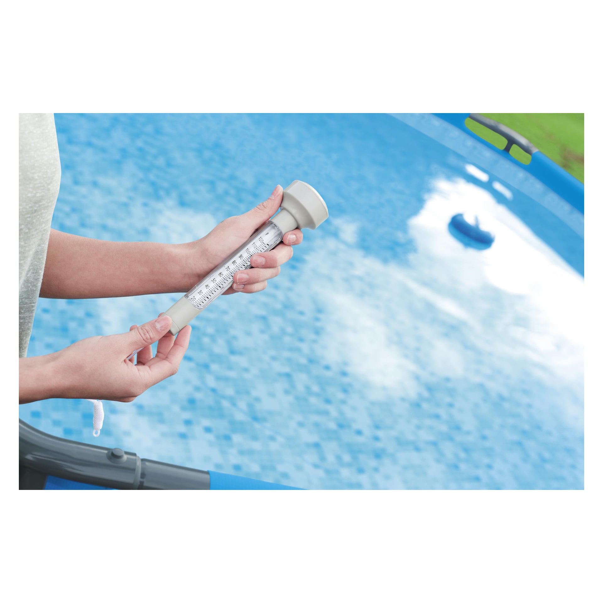 Noen sjekker temperaturen med et Bestway bassengtermometer, og holder det over et svømmebasseng med knallblått vann og synlig flisgulv.