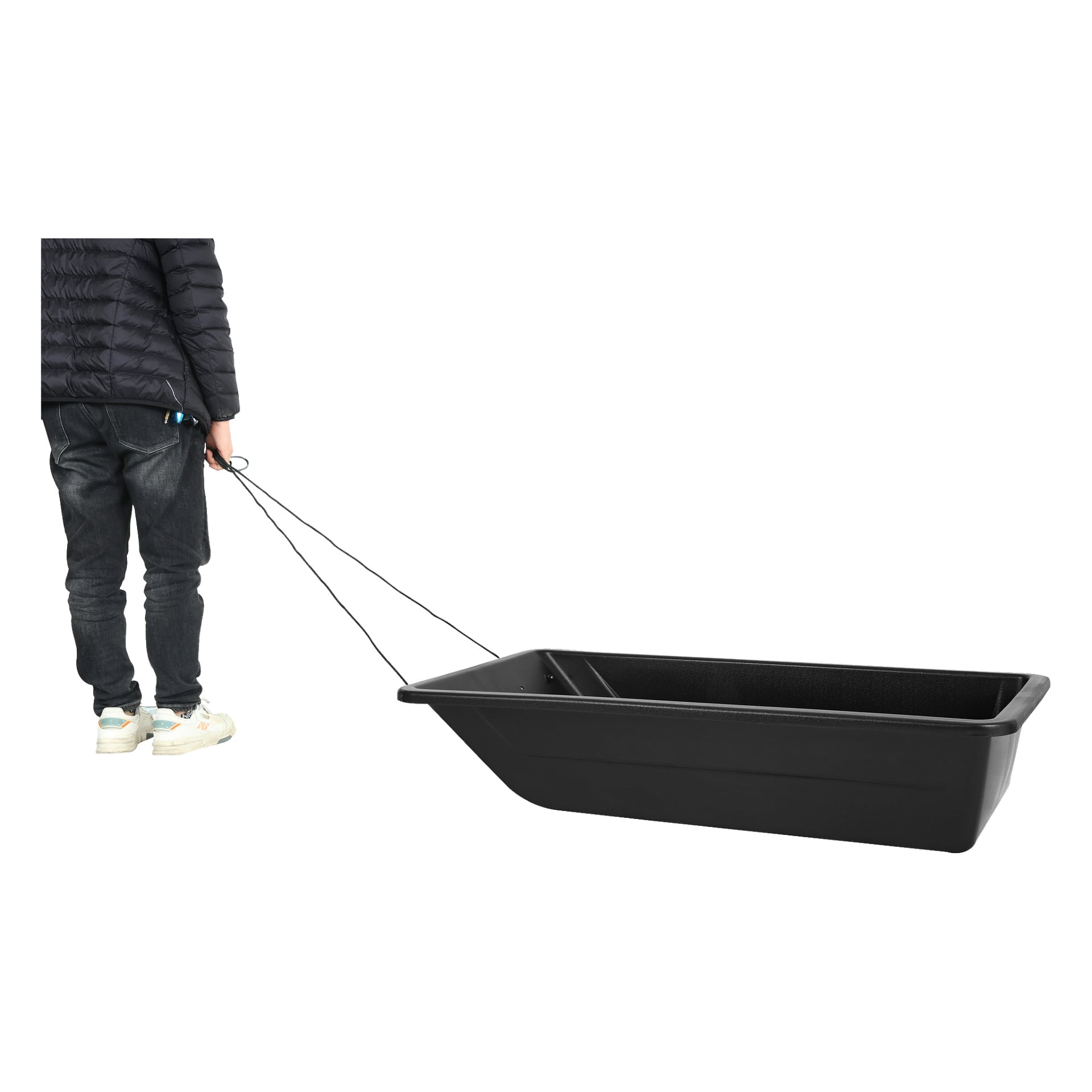 En person i jeans, sneakers och mörk jacka drar en stor, tom svart Kayoba isfiskesläde med ett rep.