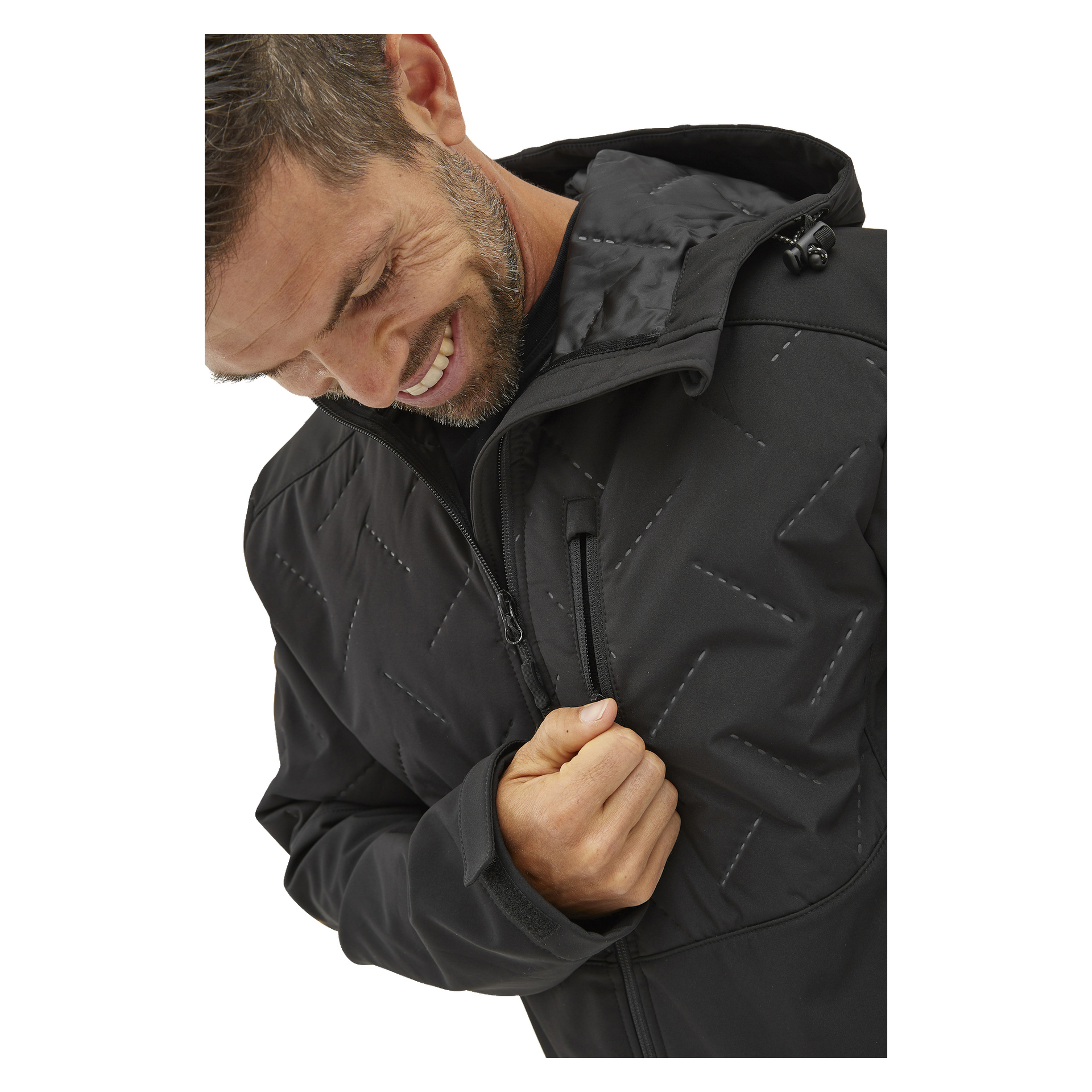 En man ler när han tittar ner och drar igen Bluewear Jerrys softshelljacka för herrar, som är lätt vadderad och har ett svart quiltmönster med diagonala sömmar och en synlig dragkedja på bröstfickan.