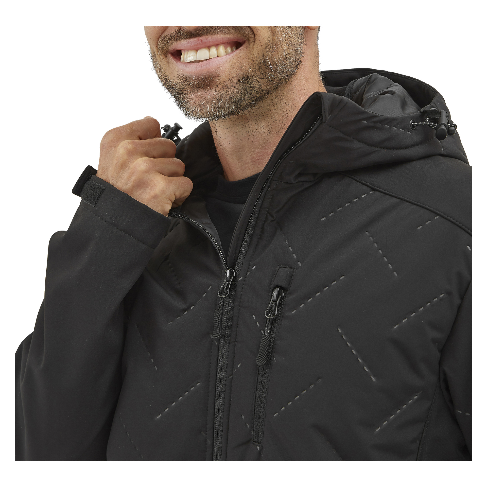 En leende man med kort skägg och mustasch bär Bluewears herrjacka Jerry softshell i svart och justerar huvan med höger hand. Jackan har synliga sömmar och fickor med dragkedja.