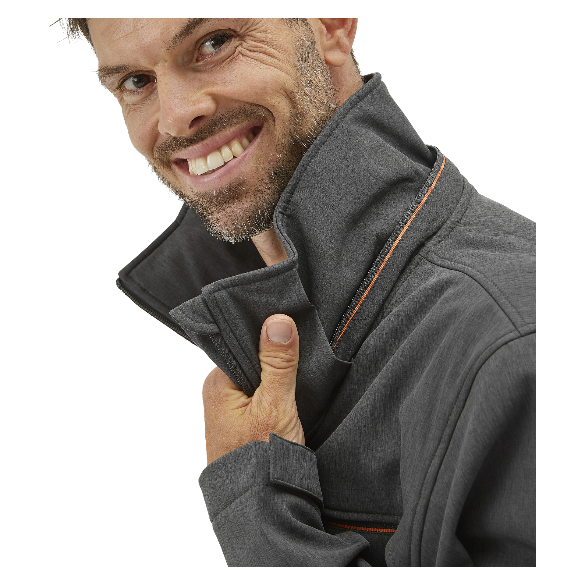 En leende man med ljust skägg lyfter kragen på en grå Bluewear Pro Workwear Pontus softshell-jacka för herrar, detaljerad med orange detaljer. Bilden är en närbild som framhäver hans ansikte och överkropp.