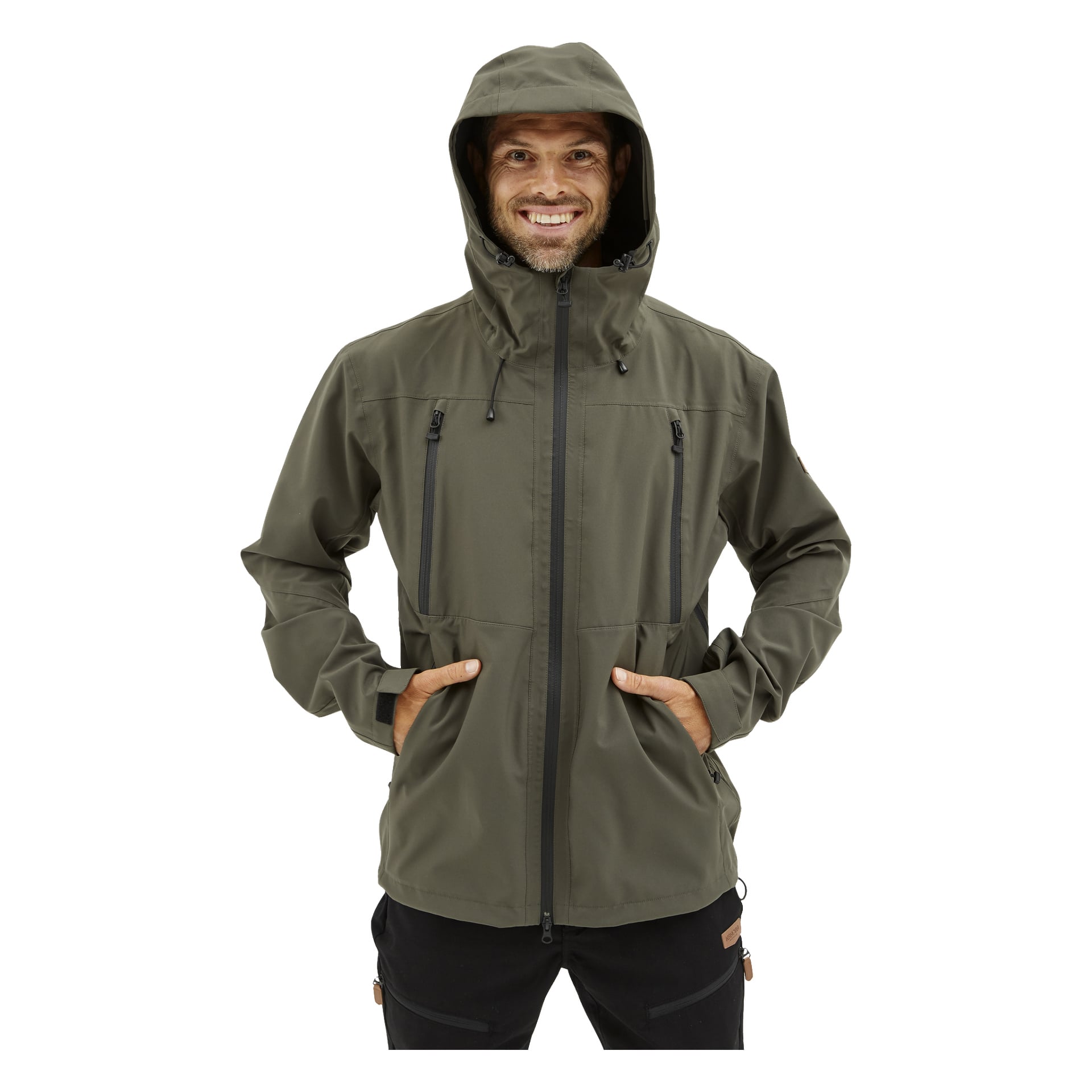 En leende man står vänd framåt med händerna i framfickorna på en olivgrön Kayoba Outdoor Men's shelljacka Helag, en huva med flera dragkedjor.