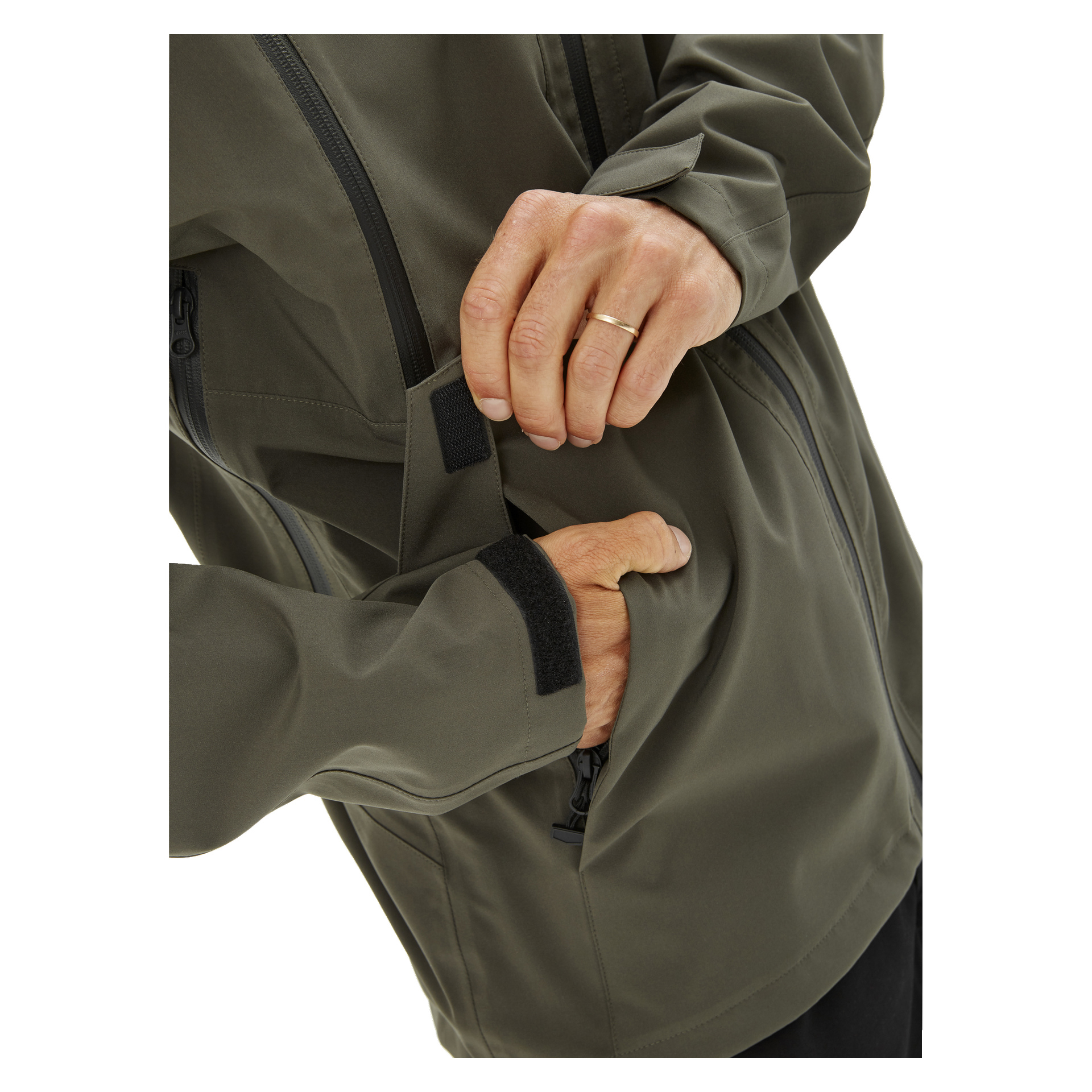 En person, som endast visas med händerna och en sektion av en olivgrön Kayoba Outdoor Men's Helag-shelljacka, säkrar en ficka med en kardborrebandsklaff. En enkel guldring sitter på vänster ringfinger.