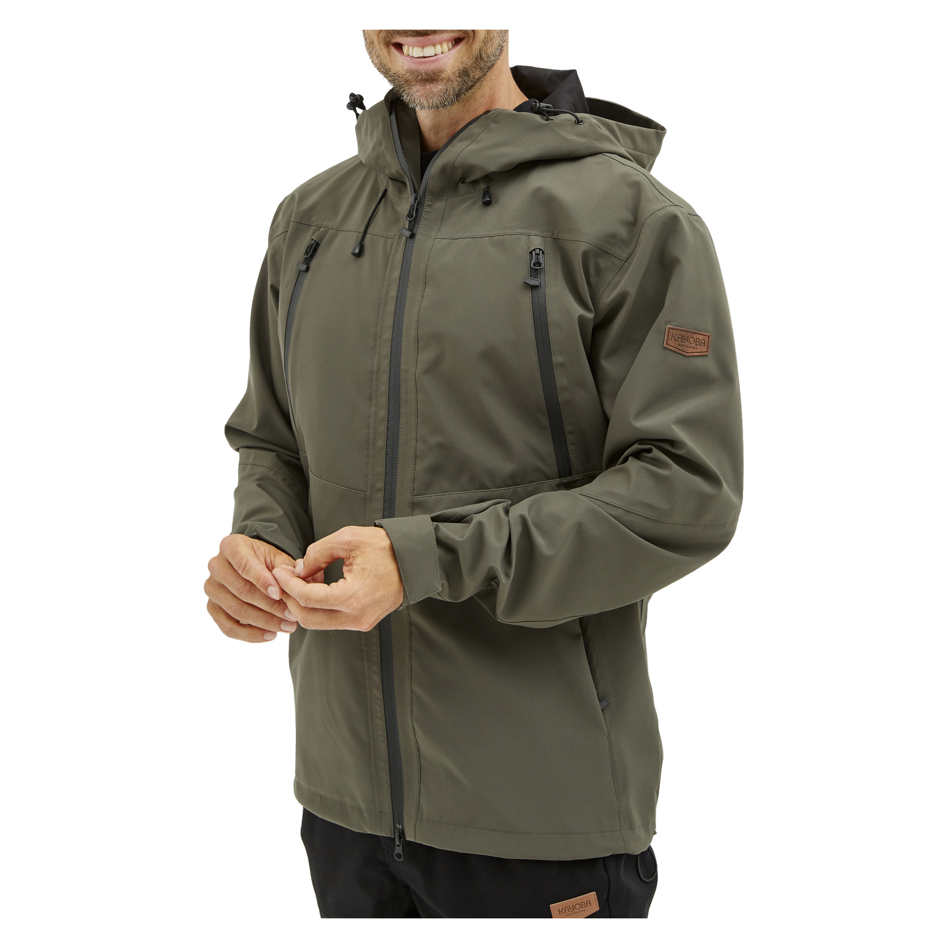 En man ler när han bär Kayoba Outdoor Men's Helag-shelljacka i olivgrönt, med svarta dragkedjor, patchdetaljer, dragkedjor på bröstet och hög krage. Han fäster en manschett på jackan.