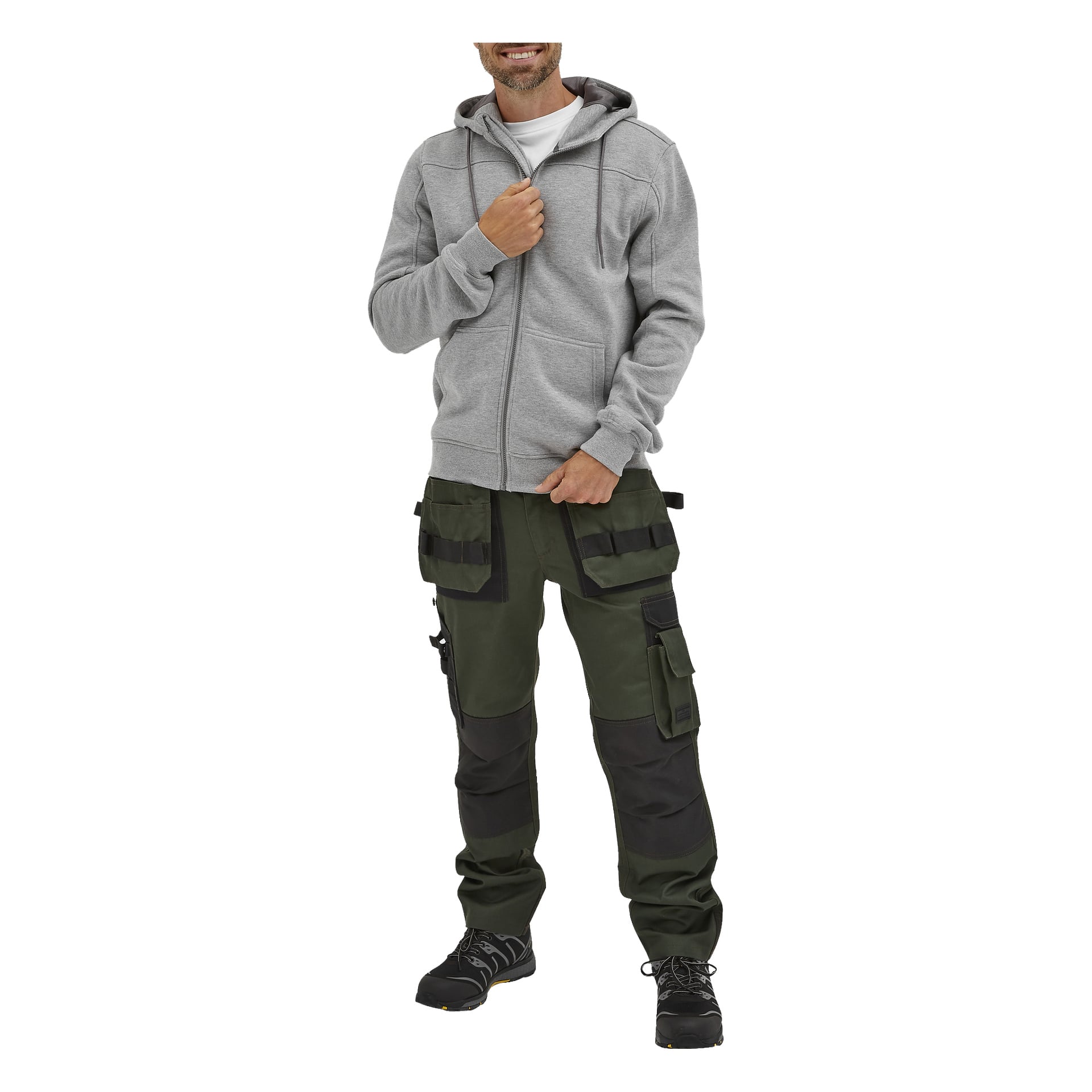 En man visas bära Bluewear Men's Anders-hoodien, en ljusgrå zip-up-stil. Han har kombinerat det med gröna och svarta arbetsbyxor med flera fickor och svarta arbetsskor. Leende håller han i dragkedjan på sin hoodie med ena handen.