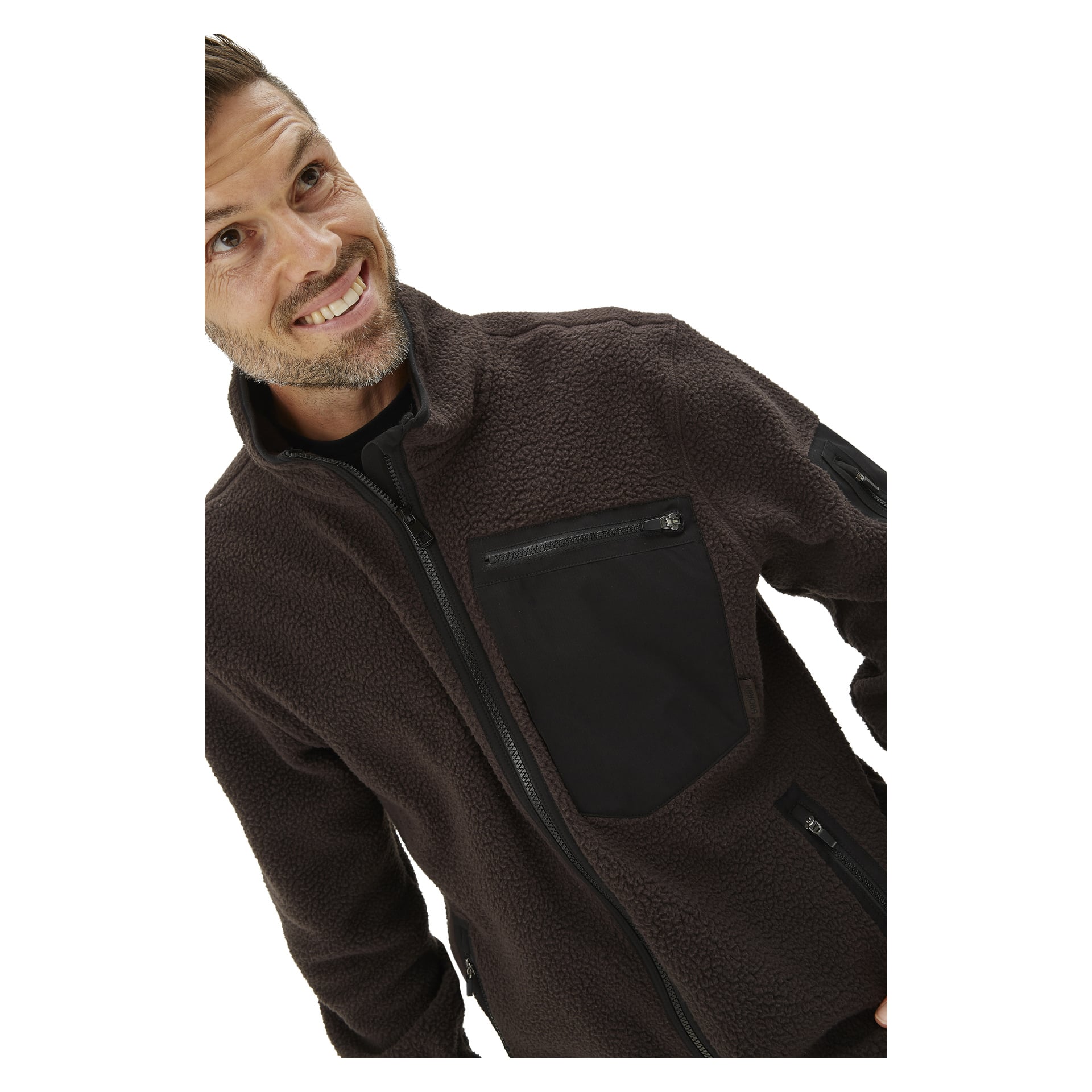 En man ler och tittar uppåt, klädd i Kayoba Outdoor Men's jacket-jackan Ljusdal, en mörkbrun fleece-zip-up med svart dragkedja och svart bröstficka.