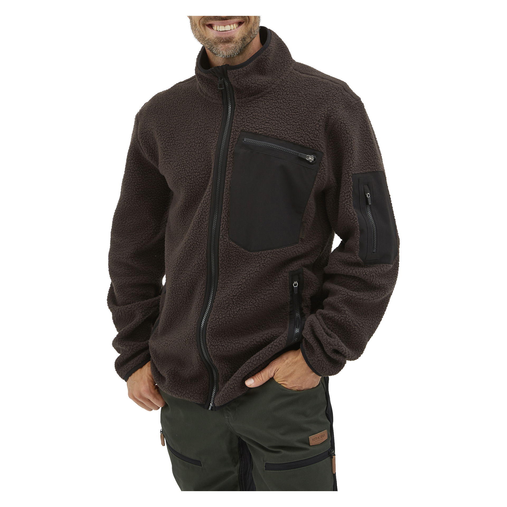 Någon visar Kayoba Outdoor Men's Ljusdal pile-jacka, en mörkbrun fleecejacka med hög krage och flera svarta fickor med dragkedja. De ler med ena handen nedstoppad i fickan, och bara överkroppen och delar av benen syns.