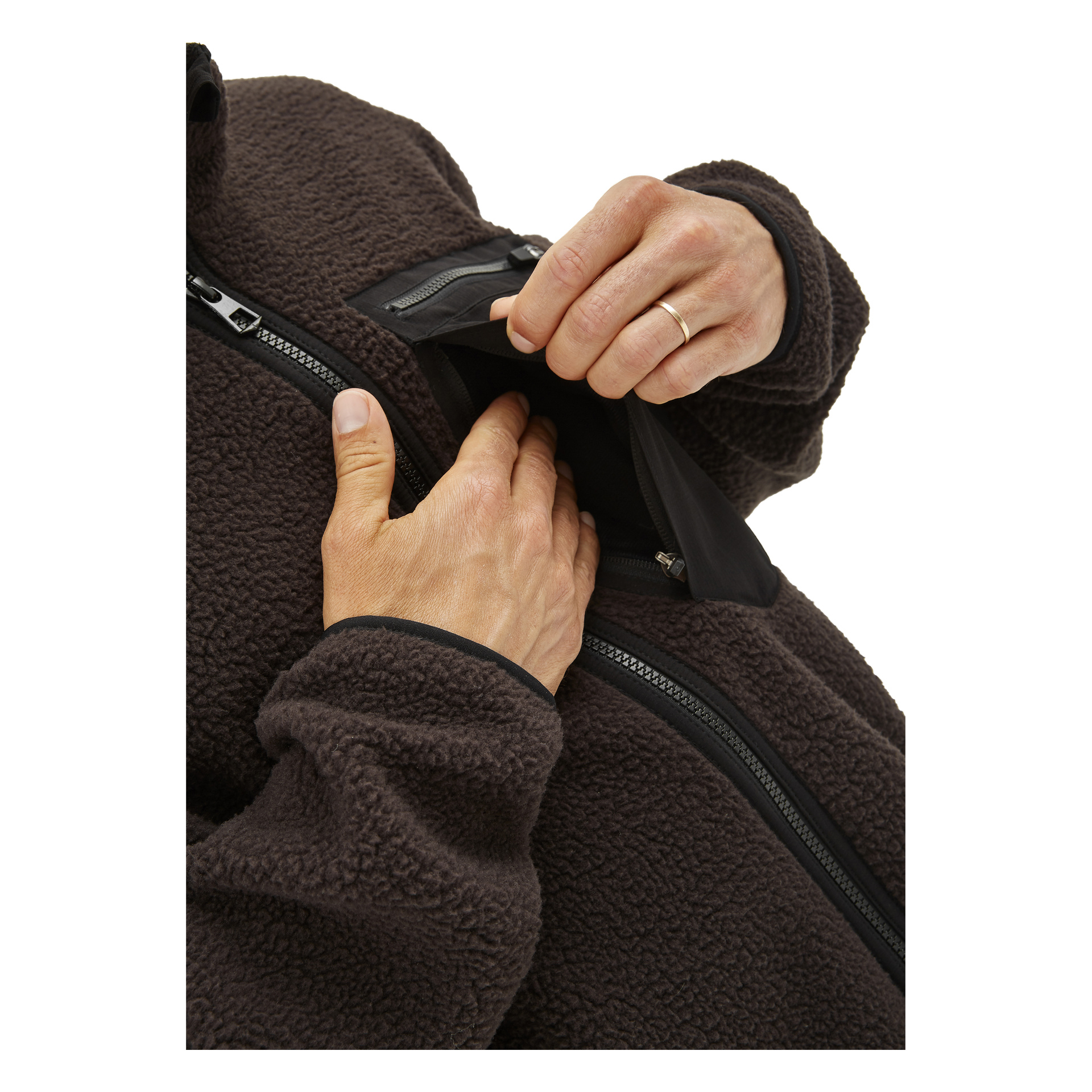 Någon klädd i en mörkbrun Kayoba Outdoor Men's pile-jacka använder Ljusdal sin vänstra hand för att dra ner dragkedjan på bröstfickan, eftersom deras högra hand delvis är inne i den. Fotot är tätt beskuret för att fokusera på händerna och fickan.