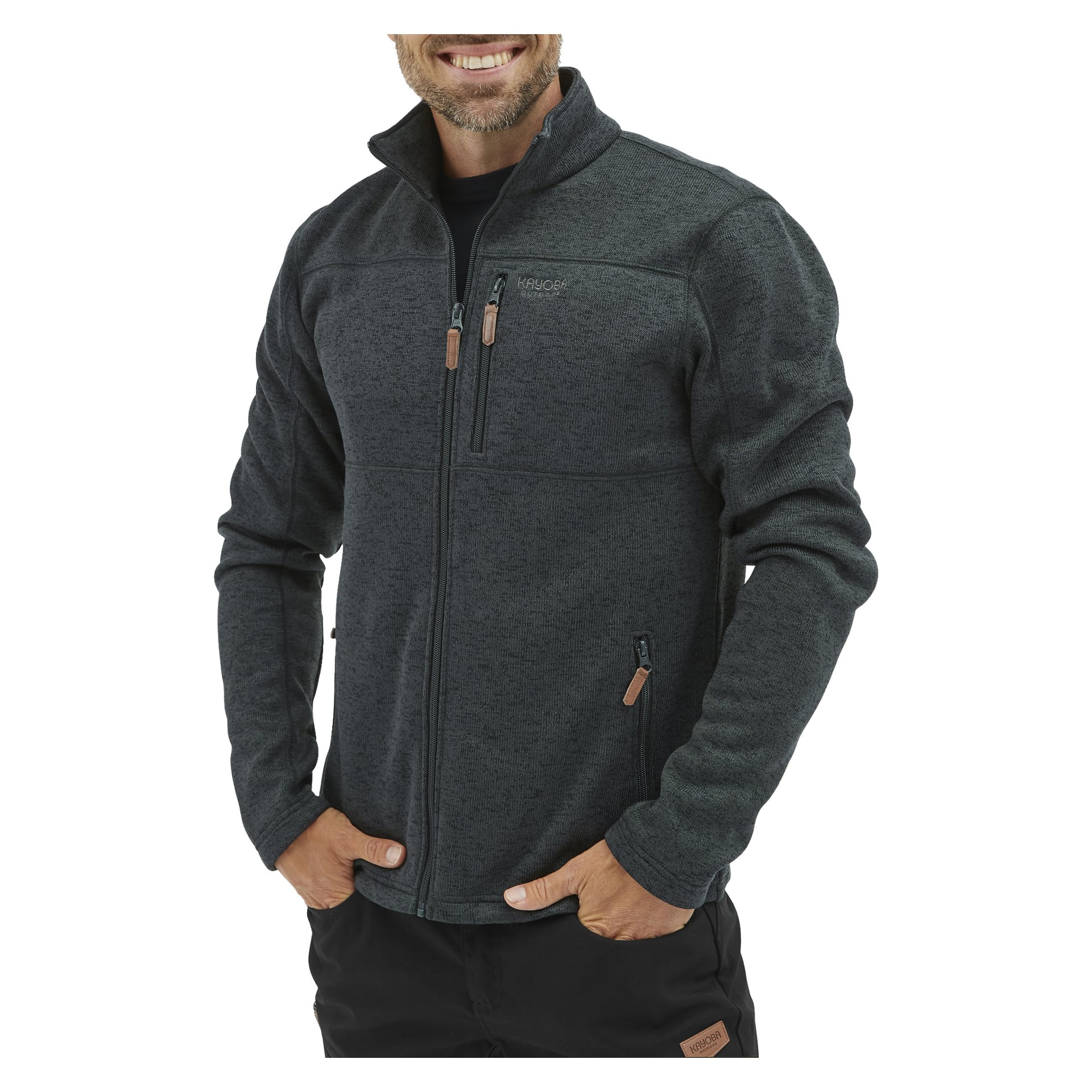 Någon ler medan de bär den mörkgrå Kayoba Outdoor Knitted Men's Fleece Jacket Malå, som har ett subtilt texturerat utseende, tre fickor med dragkedja och en liten logga på bröstet. Deras händer vilar i byxfickorna.