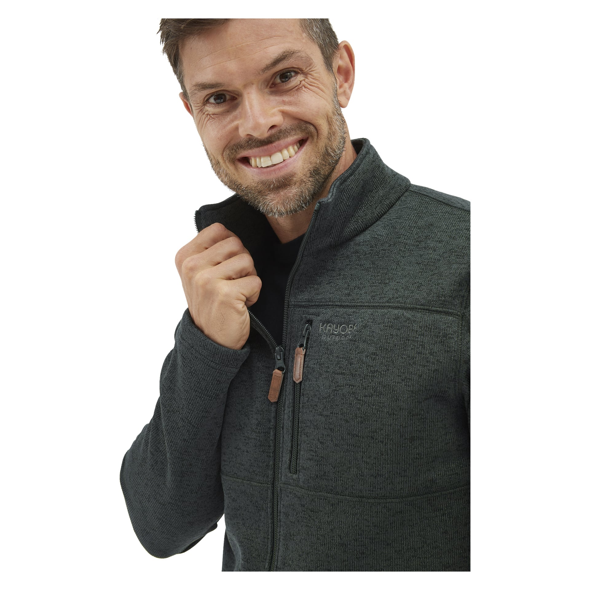 En man med kort hår och skägg ler mot kameran och håller i kragen på en Kayoba Outdoor Knitted fleecejacka för herrar, Malå, som har bröstficka och två dragkedjor.