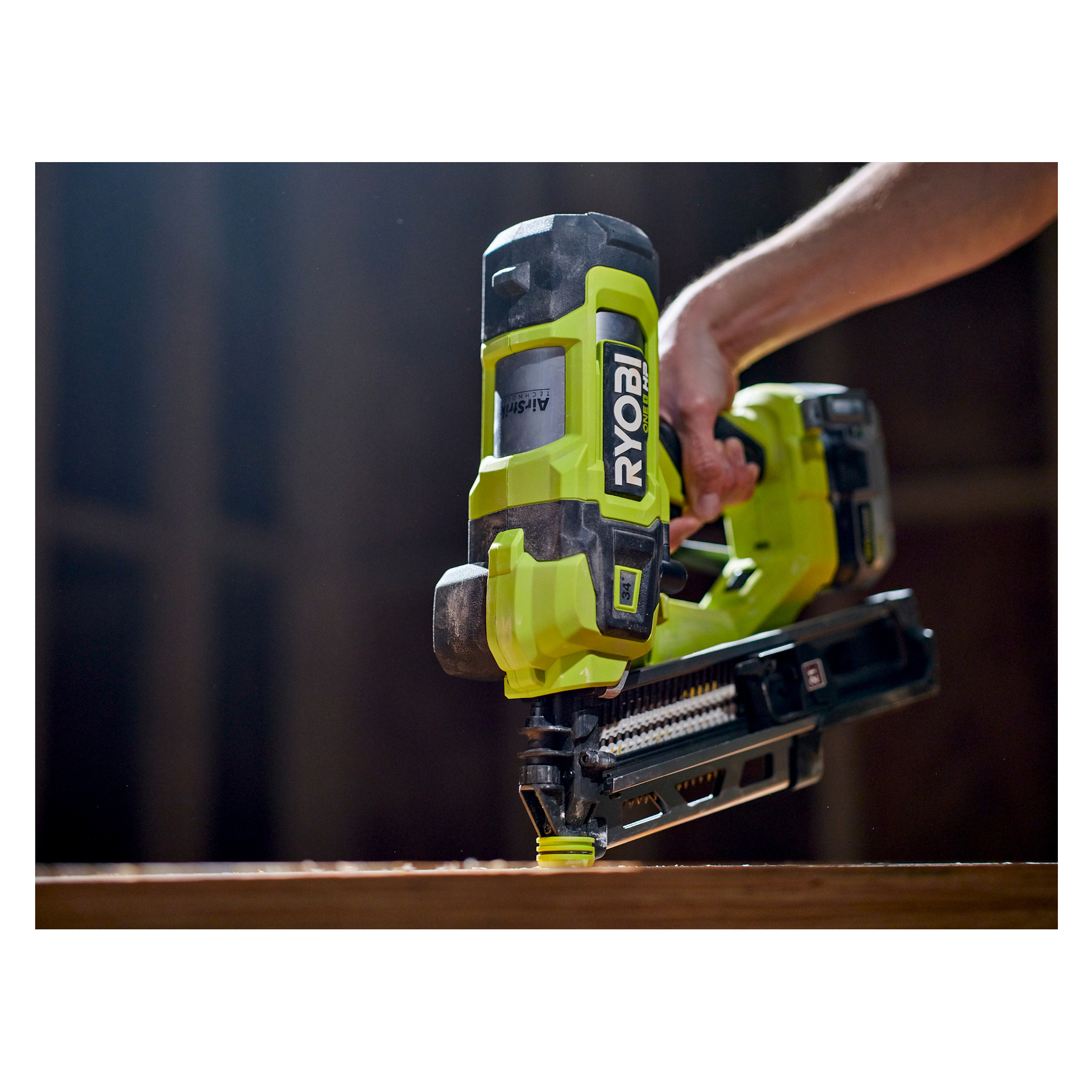 Joku käyttää vihreää Ryobi One+ HP RFN1834X-0 akkukäyttöistä naulapyssyä ja iskee naulan puuhun. Kohtaus korostaa työkalun ominaisuuksia ja brändäystä työpajassa tai rakennusympäristössä.