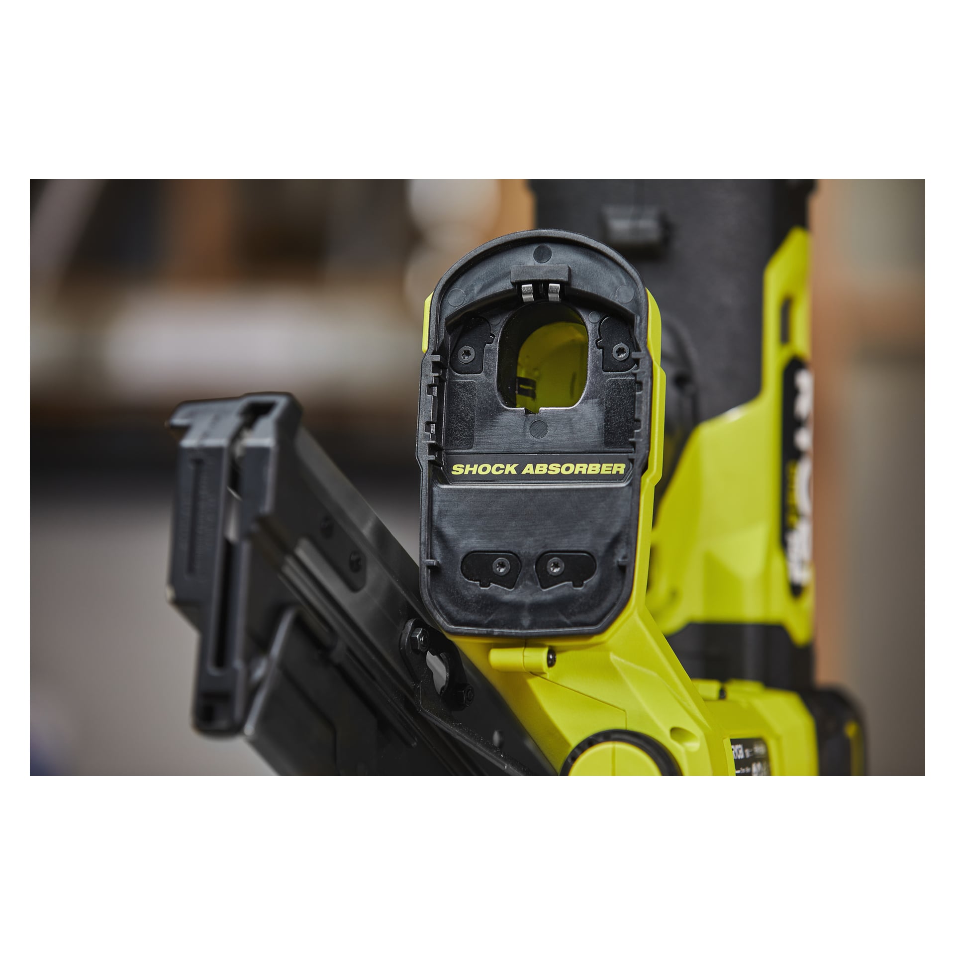 Lähikuva keltamustasta Ryobi One+ HP RFN1834X-0 -paristokäyttöisestä naulakivääristä, jossa näkyy "SHOCK ABSORBER" -merkintä yläosassa, joitakin näkyviä sisäosia ja pehmeästi sumea tausta.