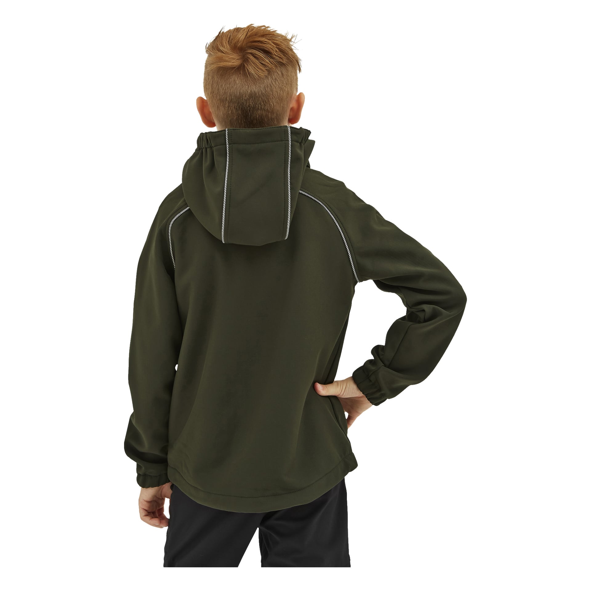 Od tyłu widzimy dziecko z krótkimi, jasnobrązowymi włosami, ubrane w ciemnozieloną kurtkę Kramfors Kayoba Outdoor Outdoor Children's softshell z lekkimi przeszyciami i czarne spodnie. Jedna ręka jest na biodrze, a druga ręka naturalnie zwisa wzdłuż ciała.