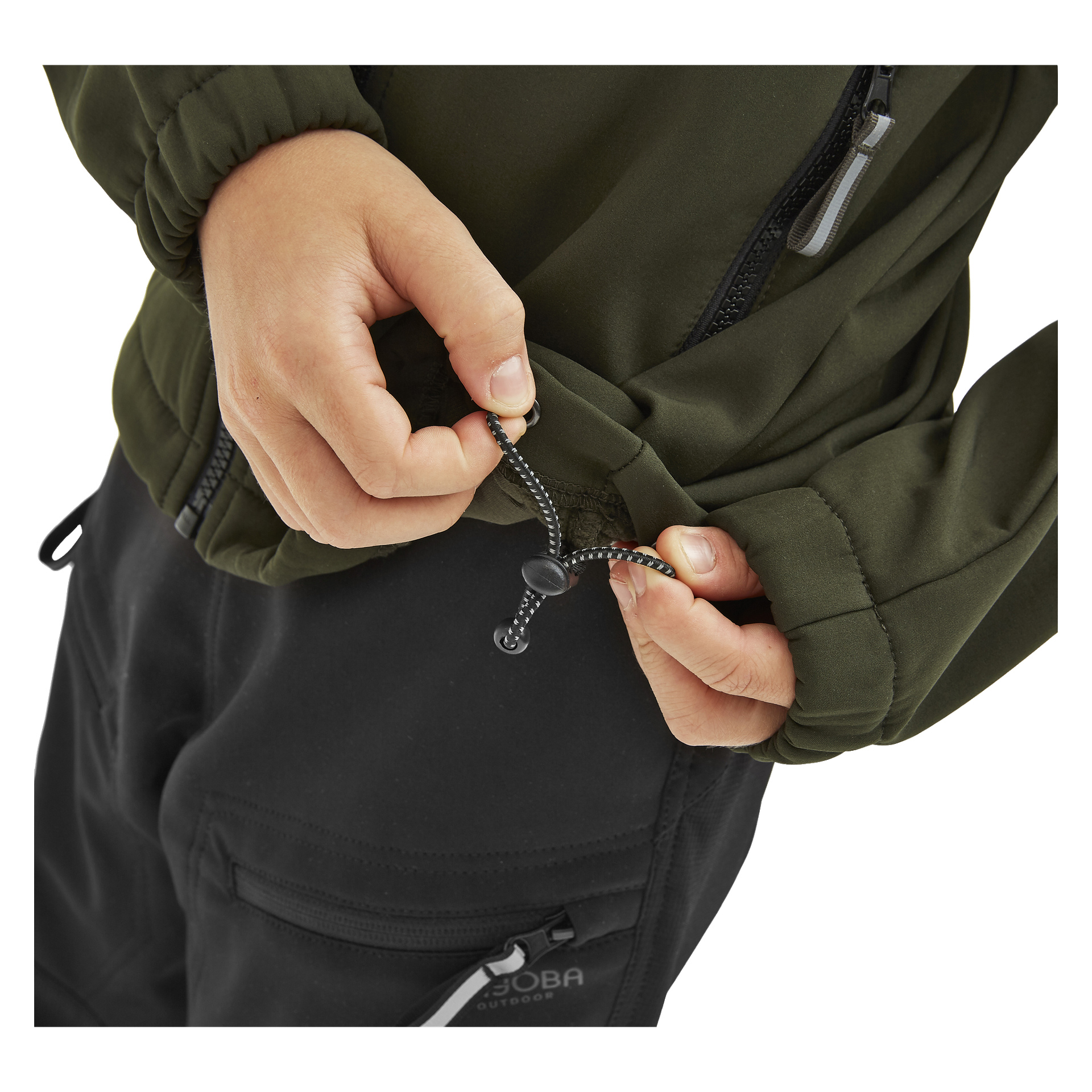 Man drar åt den elastiska dragskoen längst ner på en olivgrön Kayoba Outdoor Children's softshell-jacka Kramfors. Deras svarta byxor har dragkedjefickor, och endast händerna och överkroppen syns.