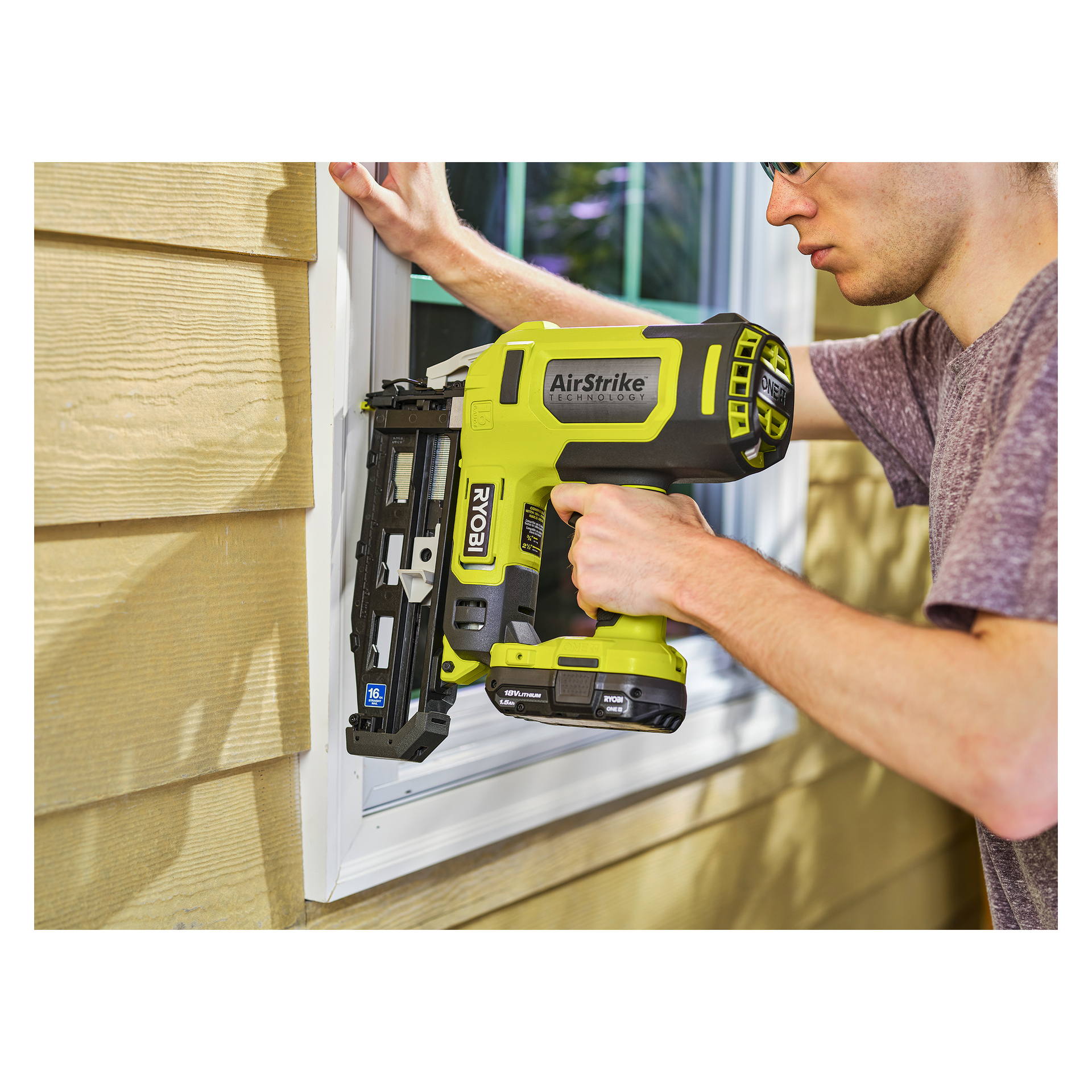 Jemand, der eine Brille und ein kurzärmeliges Hemd trägt, bedient einen Ryobi One+ Brad Gun R16GN18-0 Akku-Nagel, um Fensterleisten an einem Haus mit gelber Verkleidung zu befestigen.