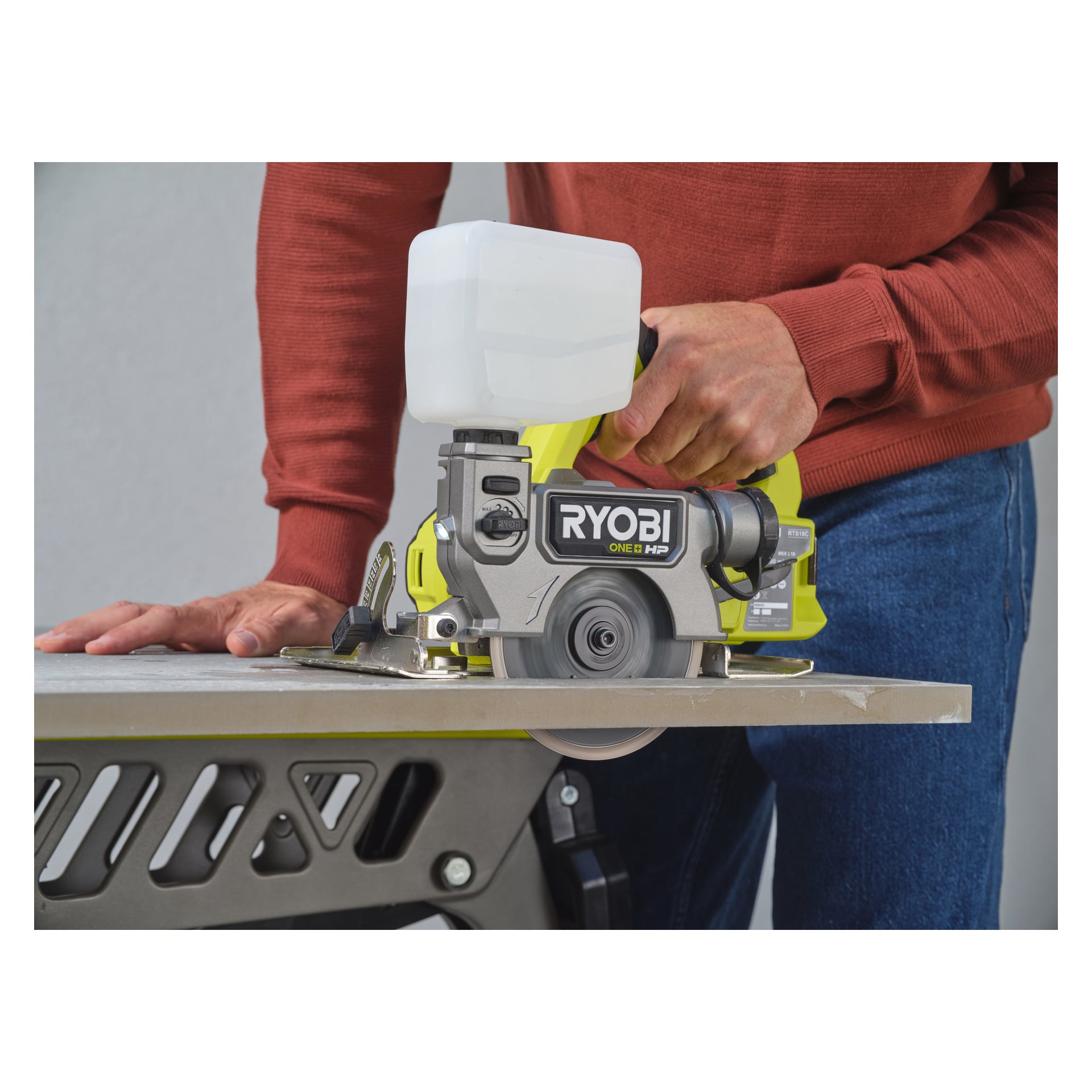 Iklädd en röd tröja hanterar man Ryobi One+ HP batteridrivna plattor och klinksåg RTS18C-0, med ena handen för att styra sågen och den andra för att hålla en platta stadigt på ett bord.