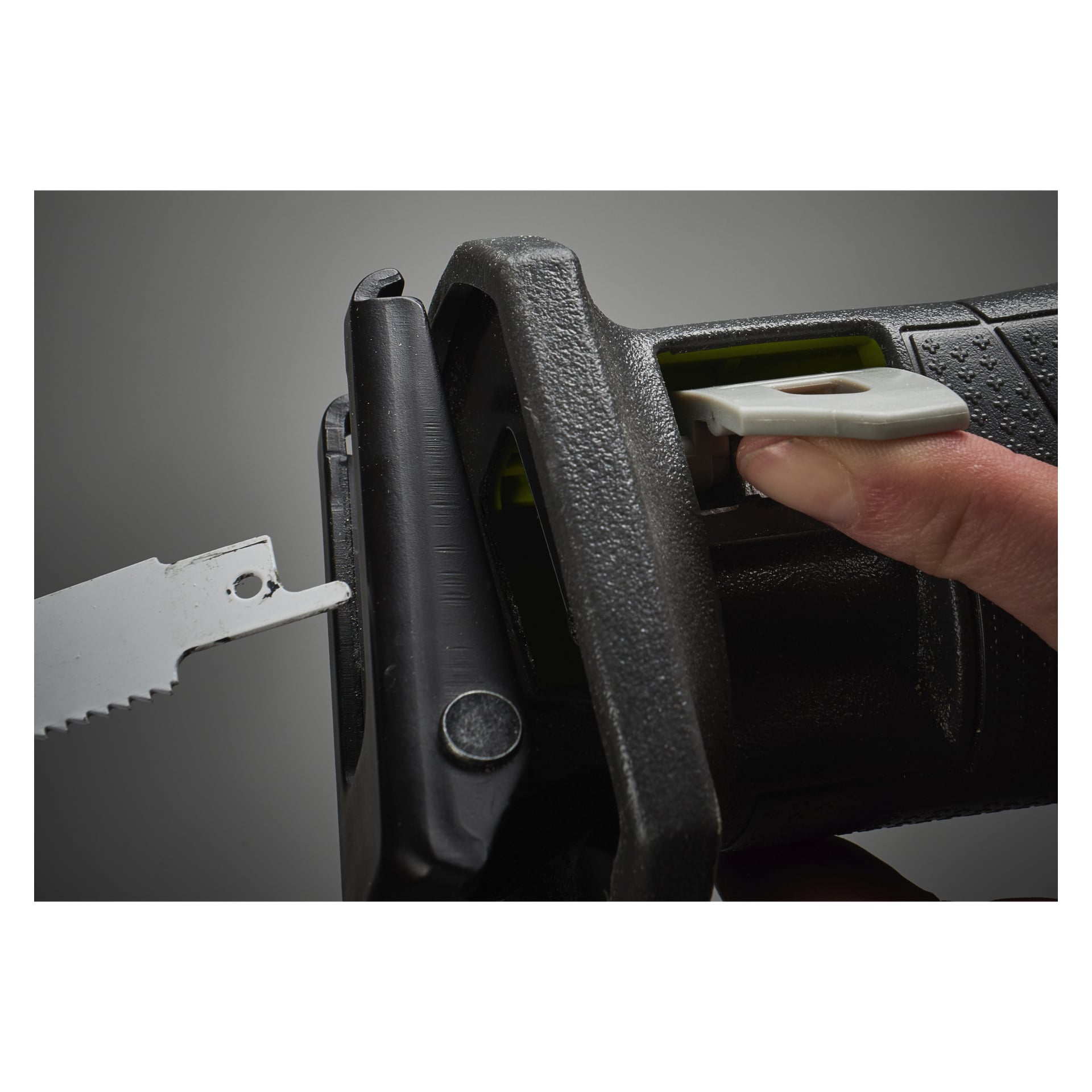 Die Hand einer Person ist zu sehen, wie sie einen grauen Hebel loslässt, um das Sägeblatt einer schwarzen Ryobi One+ R18RS-0 batteriebetriebenen Kolbensäge zu wechseln, wobei das Blatt teilweise in den Halter eingesteckt ist.