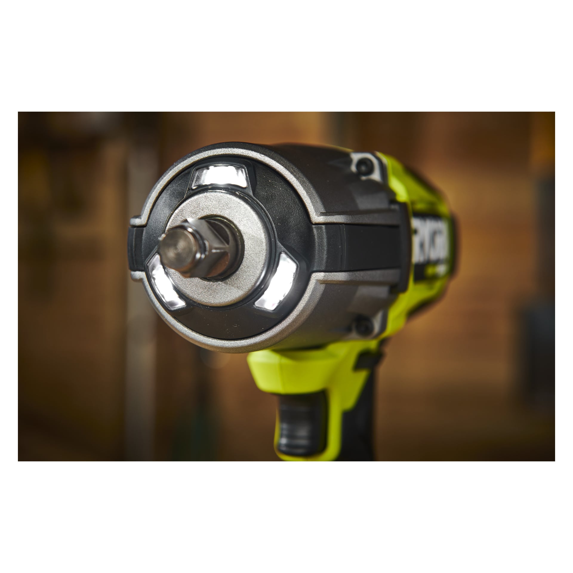 Nahaufnahme des Ryobi One+ HP Schlagschrauberschlüssels und Mini-Kompressors RIW18XPI-0 | R18PI-0 Set, ausgestattet mit dem kabellosen Schlagschrauberschlüssel mit eingebauten LED-Lichtern in der Nähe der Steckdose und einem markanten grün-schwarzen Farbschema, das vor einem sanft verschwommenen Werkstattinterieur gezeigt wurde.