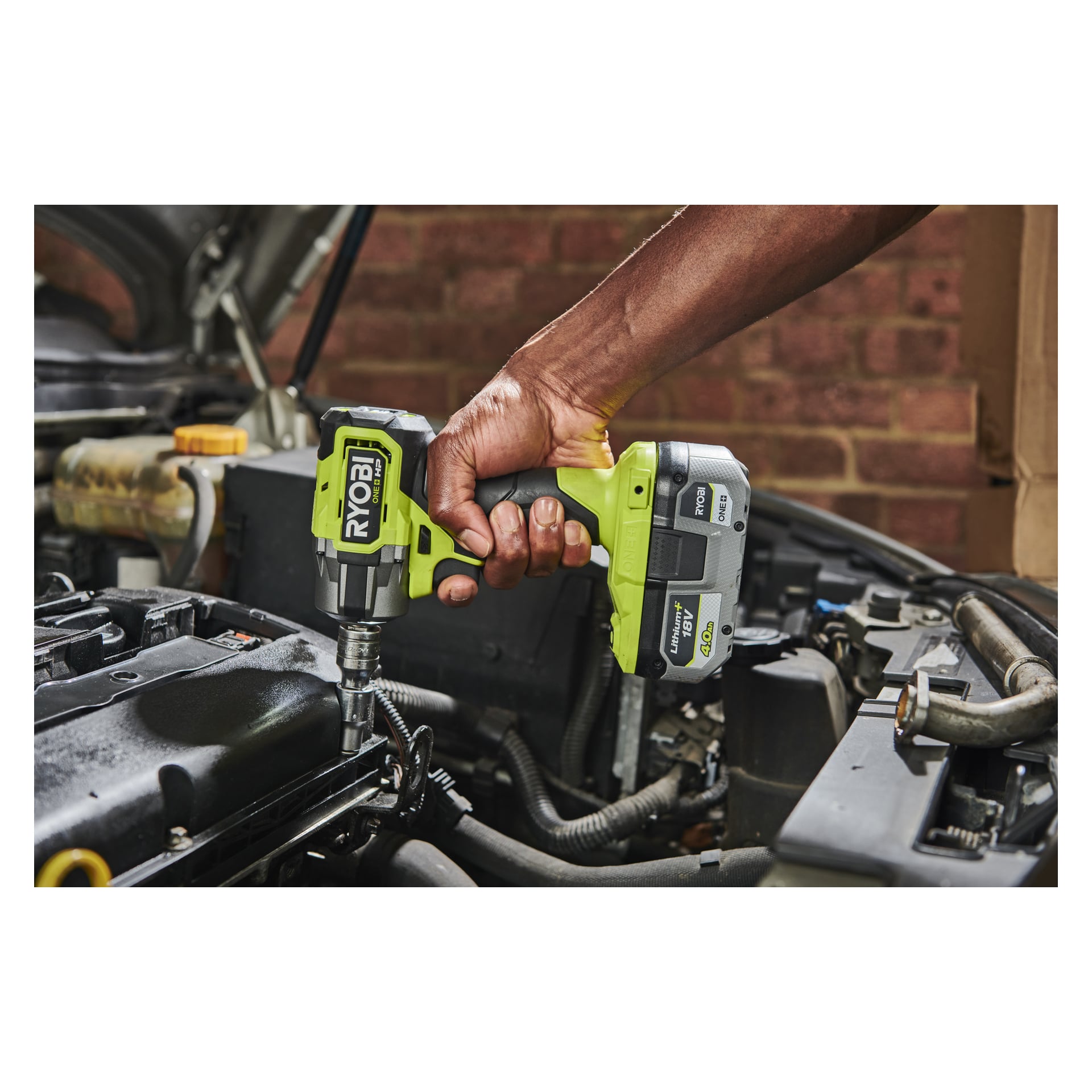 Joku käyttää Ryobi One+ HP Impact Wrench RIW18C-0 -moottoria auton moottorilla autotallissa, jonka takana on tiiliseinä. Auton konepelti on auki, paljastaen useita moottorin osia.