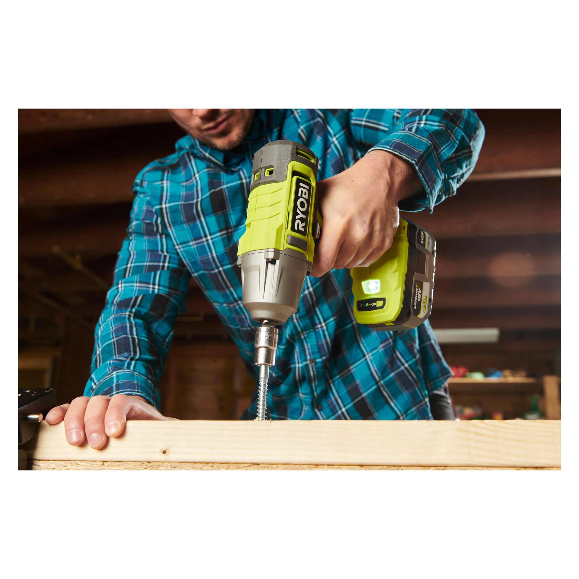Med en blå rutig skjorta använder man en Ryobi One+ Impact Wrench RIW18-0 för att fästa en stor skruv i en träbit inuti.
