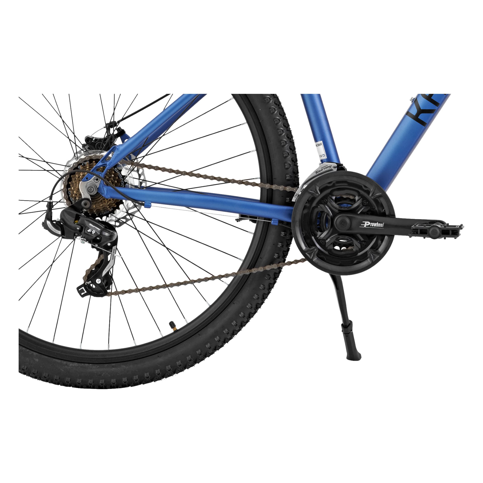 Detaljerad vy av Kayoba Mountain Bike Walder, med fokus på det blå bakhjulet, drivlinan inklusive kedja, växlar och växel, samt pedalvev och ett svart stöddel som sträcks ner till marken.