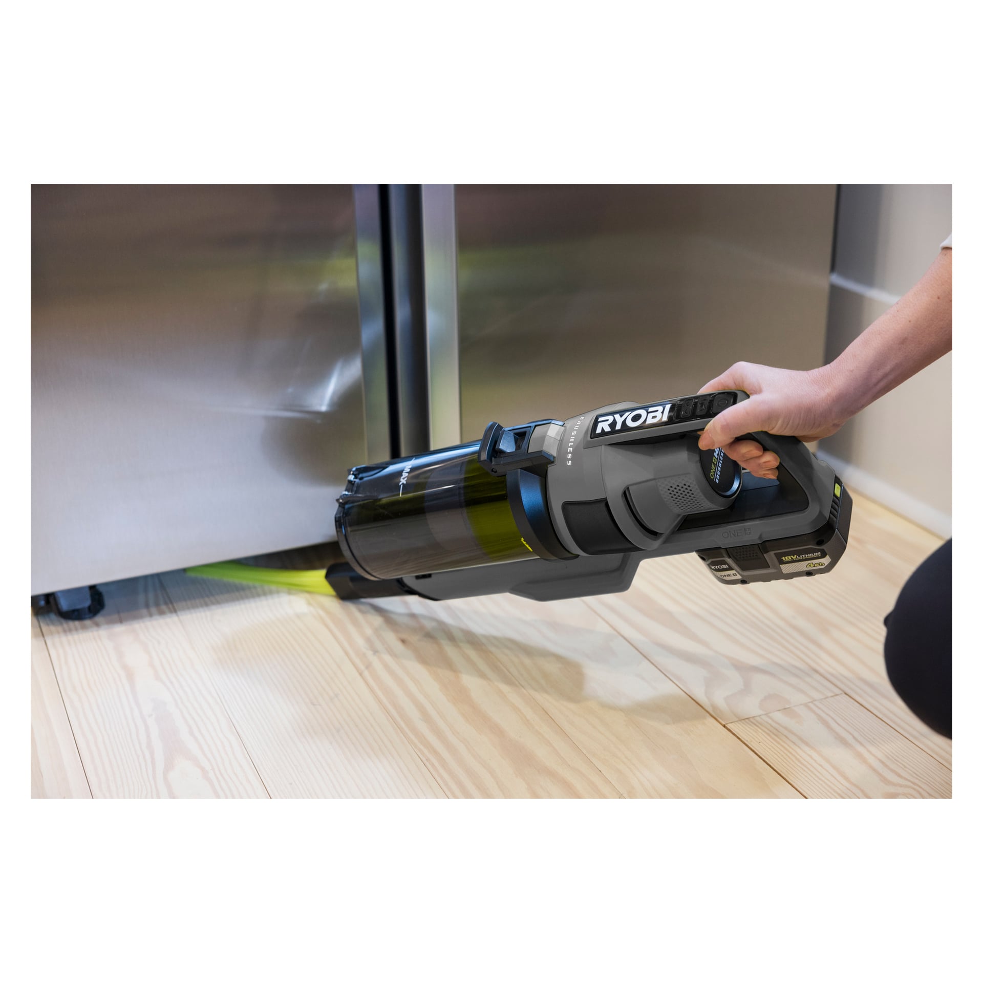 Joku käyttää Ryobi One+ pystysuoraa imuria (RSVS18BL-0, harjaton moottori) niin, että se ulottuu ruostumattomasta teräksestä valmistetun jääkaapin alle kevyellä puulattialla, ja imurin suutin ulottuu jääkaapin alapuolelle tiukkaan rakoon.