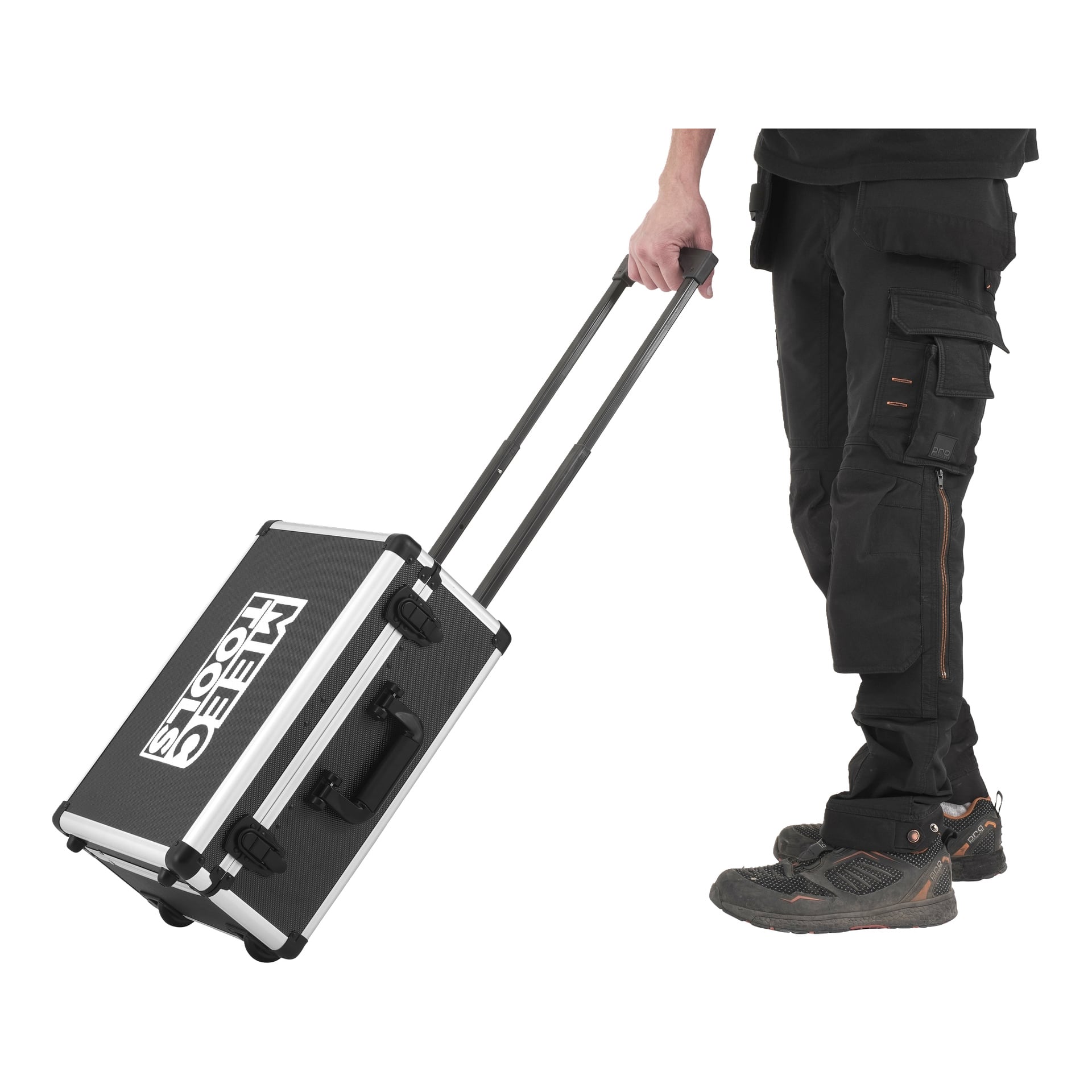 Osoba ubrana w czarne spodnie robocze i buty jest pokazana, jak ciągnie czarno-srebrną walizkę Meec Tools na kółkach, z wysuniętą rękojeścią. Widoczne są tylko dolne partie ciała i futerał z narzędziami. Na boku etui widnieje nazwa Meec Tools.
