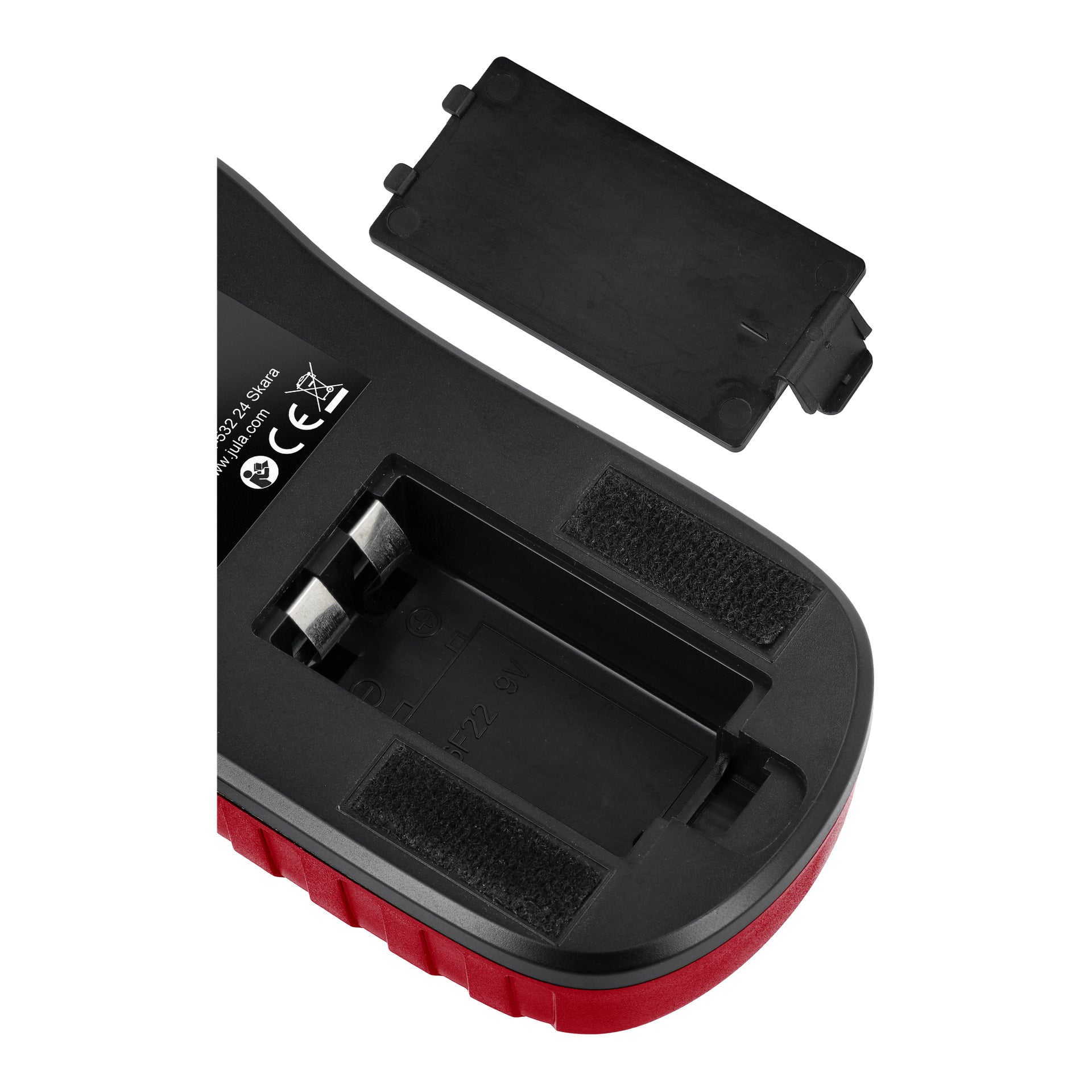 En närbild av en svart och röd Meec Tools Multi-detektor visar batterifacket öppet, locket borttaget och vilande ovanpå, vilket exponerar batteripolerna inuti.