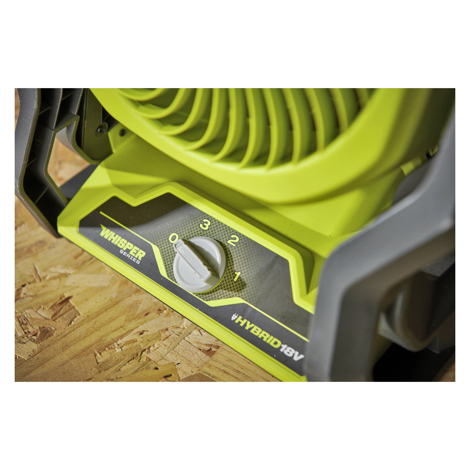 Närbild av en grön Ryobi One+ RF18-0 batterifläkt, med ratten inställd på 2, märkt "WHISPER SERIES" och "HYBRID 18V" på träyta.