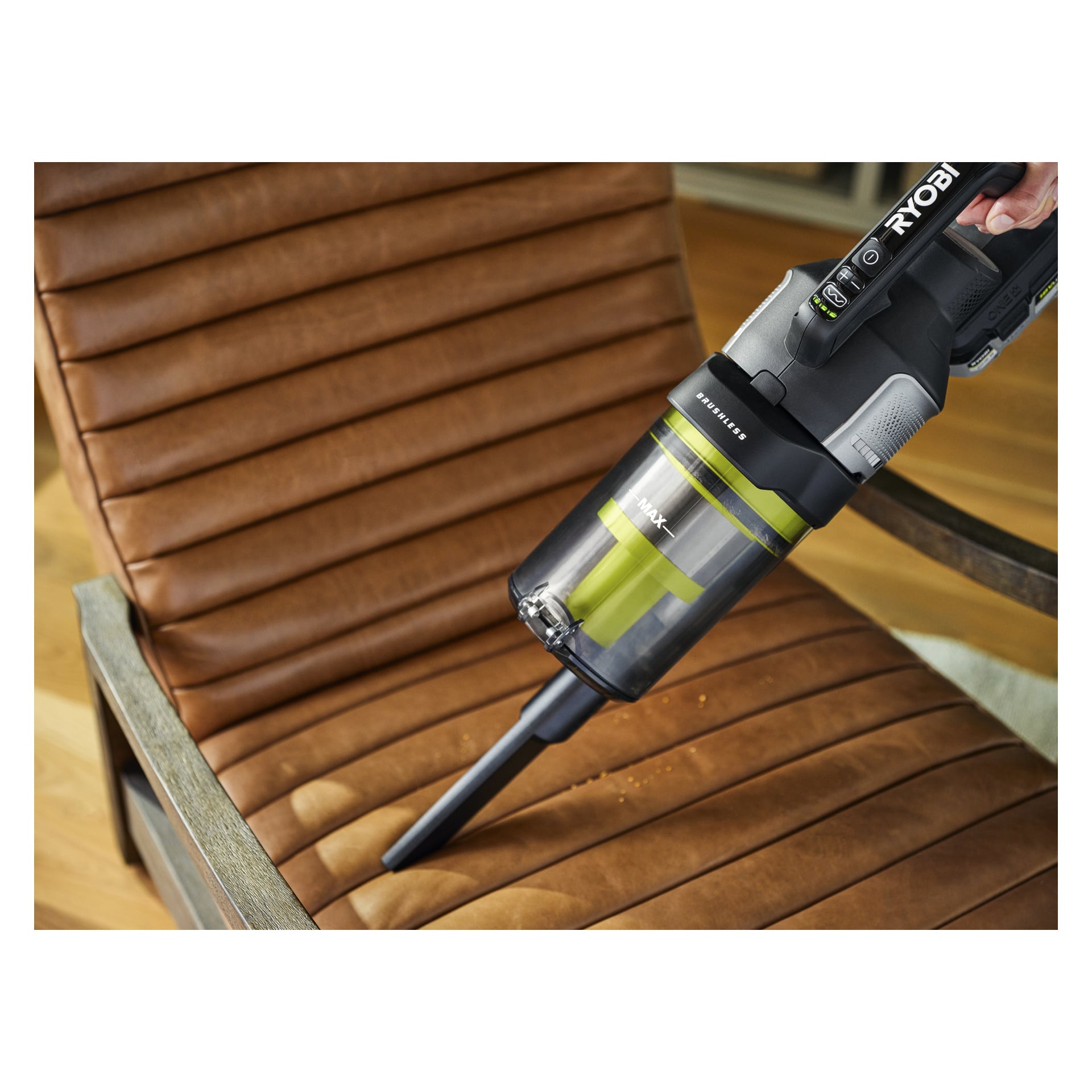 En Ryobi One+ Upright Vacuum Cleaner Premium RASV18BL-1X40G tar bort smulor från en brun läderstol.