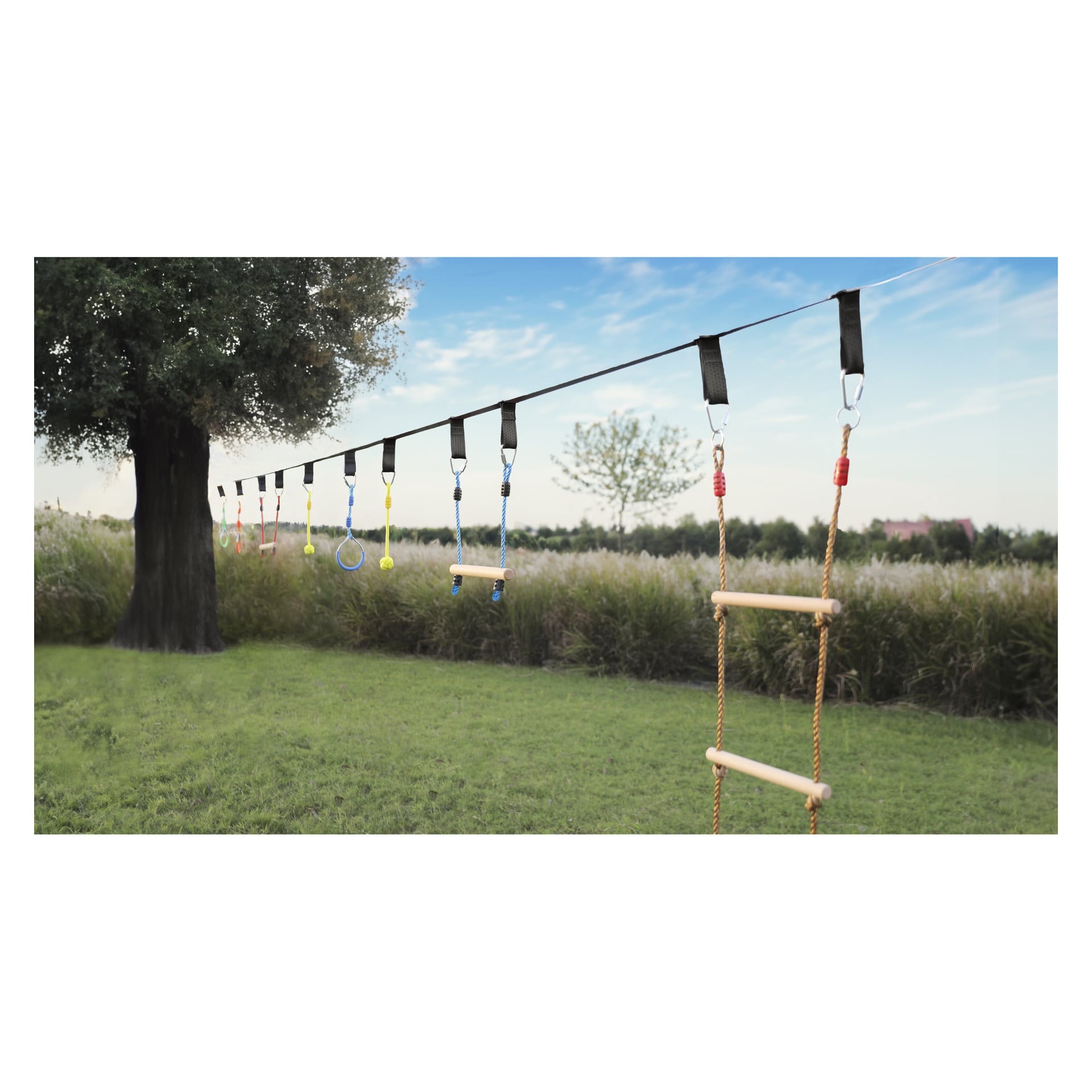 13-osainen Kayoba Slackline -setti on venytetty kahden puun väliin, ja siinä on renkaita, tankkoja ja köysitikkaita nurmikon yllä.