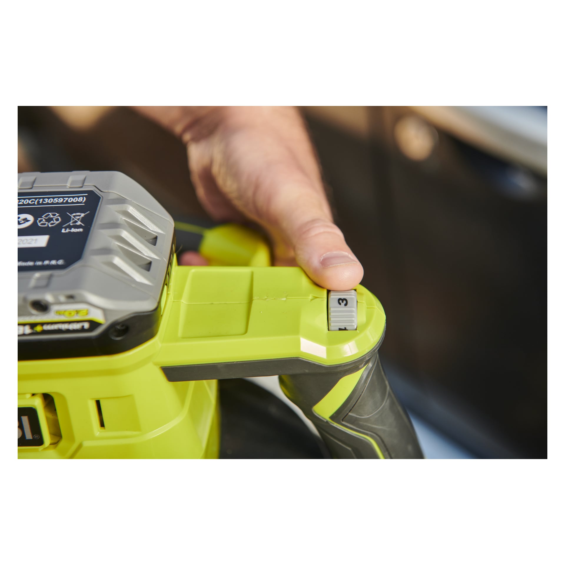 Ręka obraca numerowany pokrętło w Ryobi One+ Oscillating Polisher RBP18250-0, podkreślając jego zielono-czarne korpus, baterię i uchwyt.