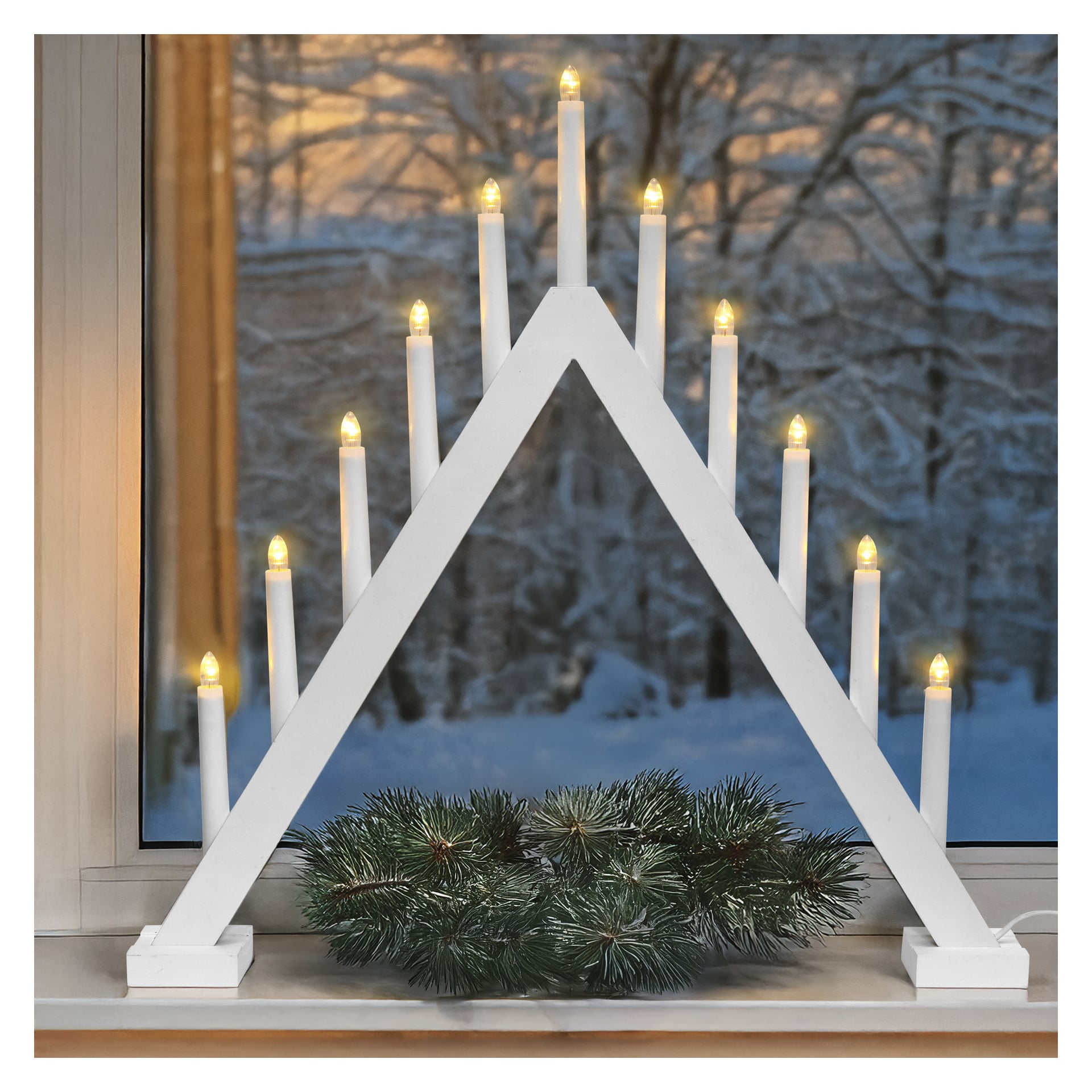 EKVIP Large LED adventtikynttilänjala, jossa on yksitoista valoa valkoisessa kolmiossa, sijaitsee ikkunalaudalla männynoksien ja lumisten puiden yläpuolella.