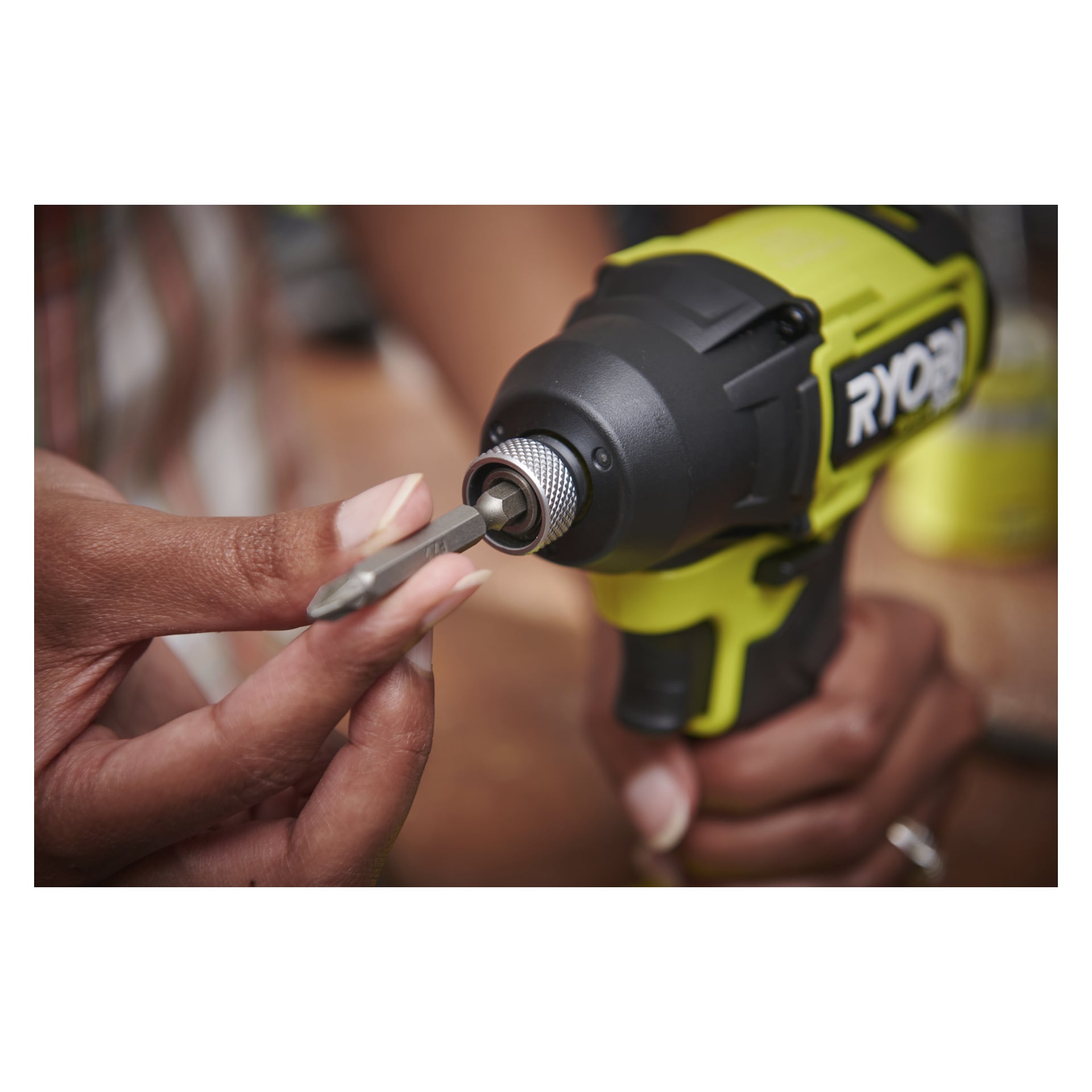 Man sätter in en skruvmejselbit i den gula och svarta Ryobi One+ HP Brushless slagskruvskruven RID18C1-0 med fingrarna.