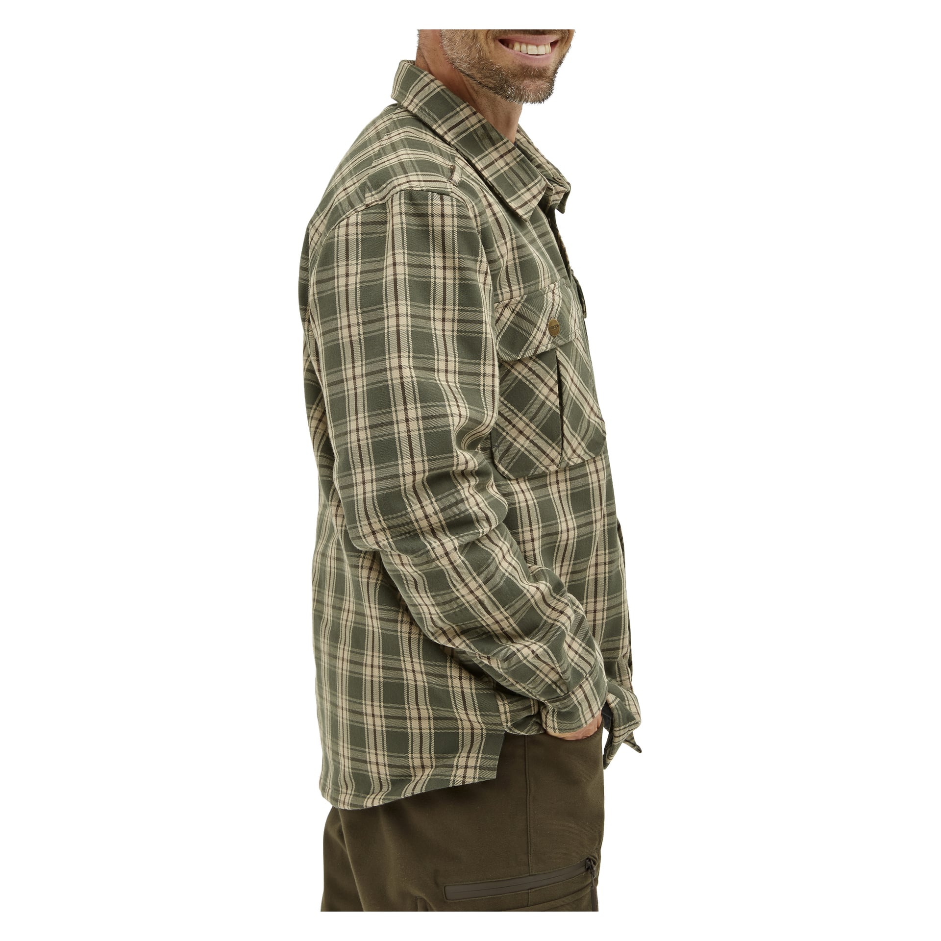 Mężczyzna z boku się uśmiecha, ubrany w zielono-beżową kraciastę flanelową koszulę Kayoba Outdoor Grimsö, ciemne spodnie, lewą rękę w kieszeni.