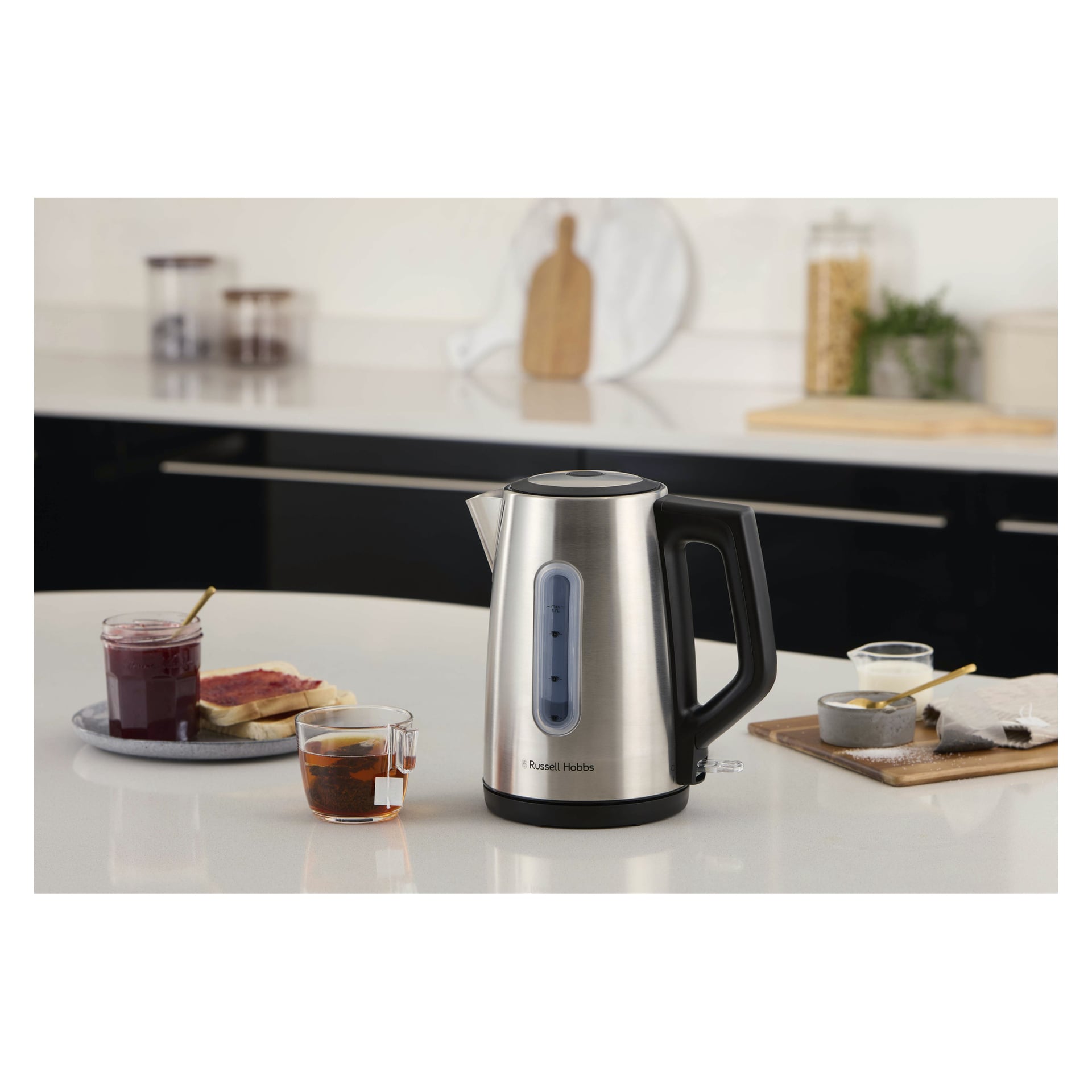 En Russell Hobbs Heaton-vattenkokare på en köksbänk bredvid te, sylt, rostat bröd med sylt, små skålar och diverse köksartiklar.