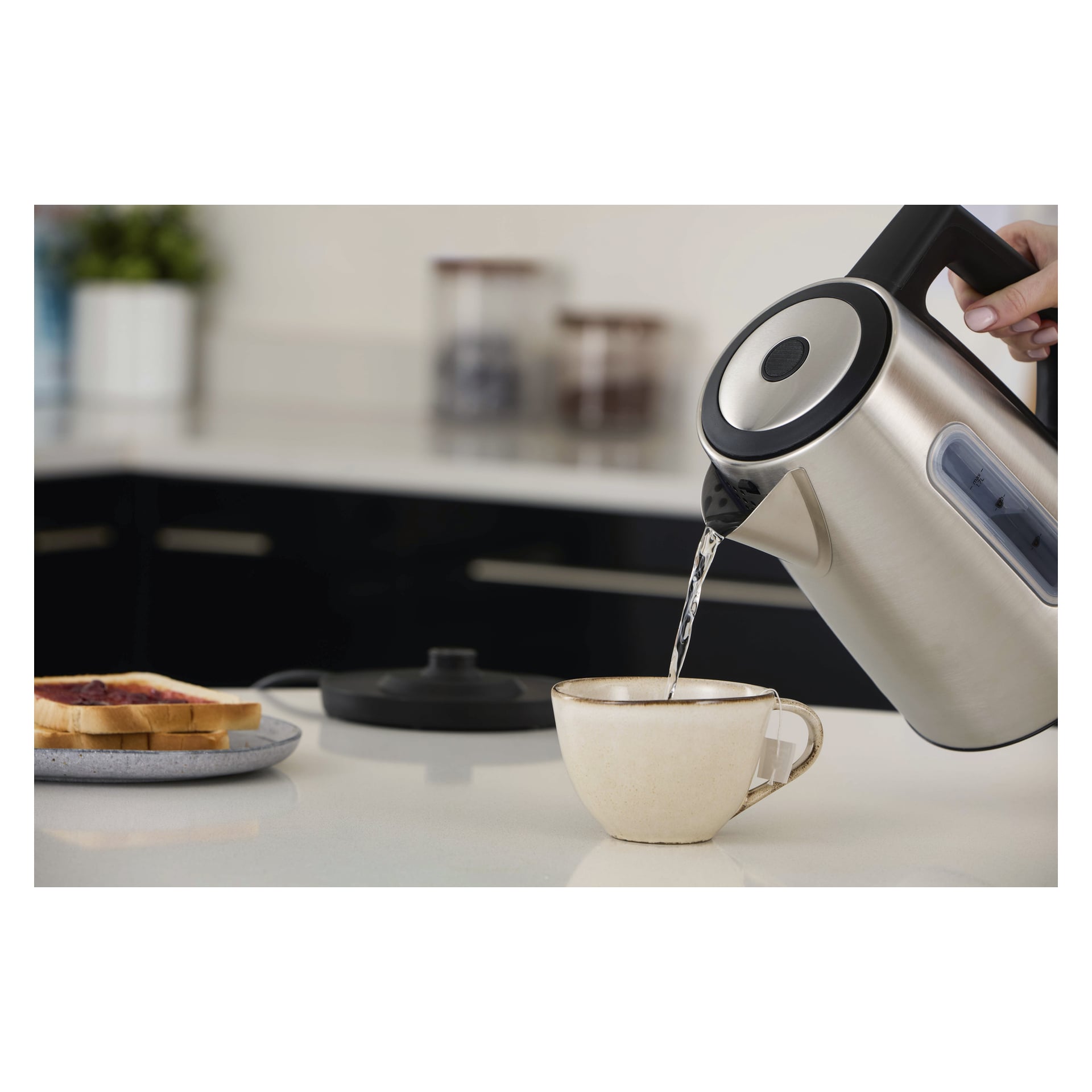 Hett vatten hälls från en Russell Hobbs Kettle Heaton i en mugg bredvid rostat bröd och sylt på köksbänken.