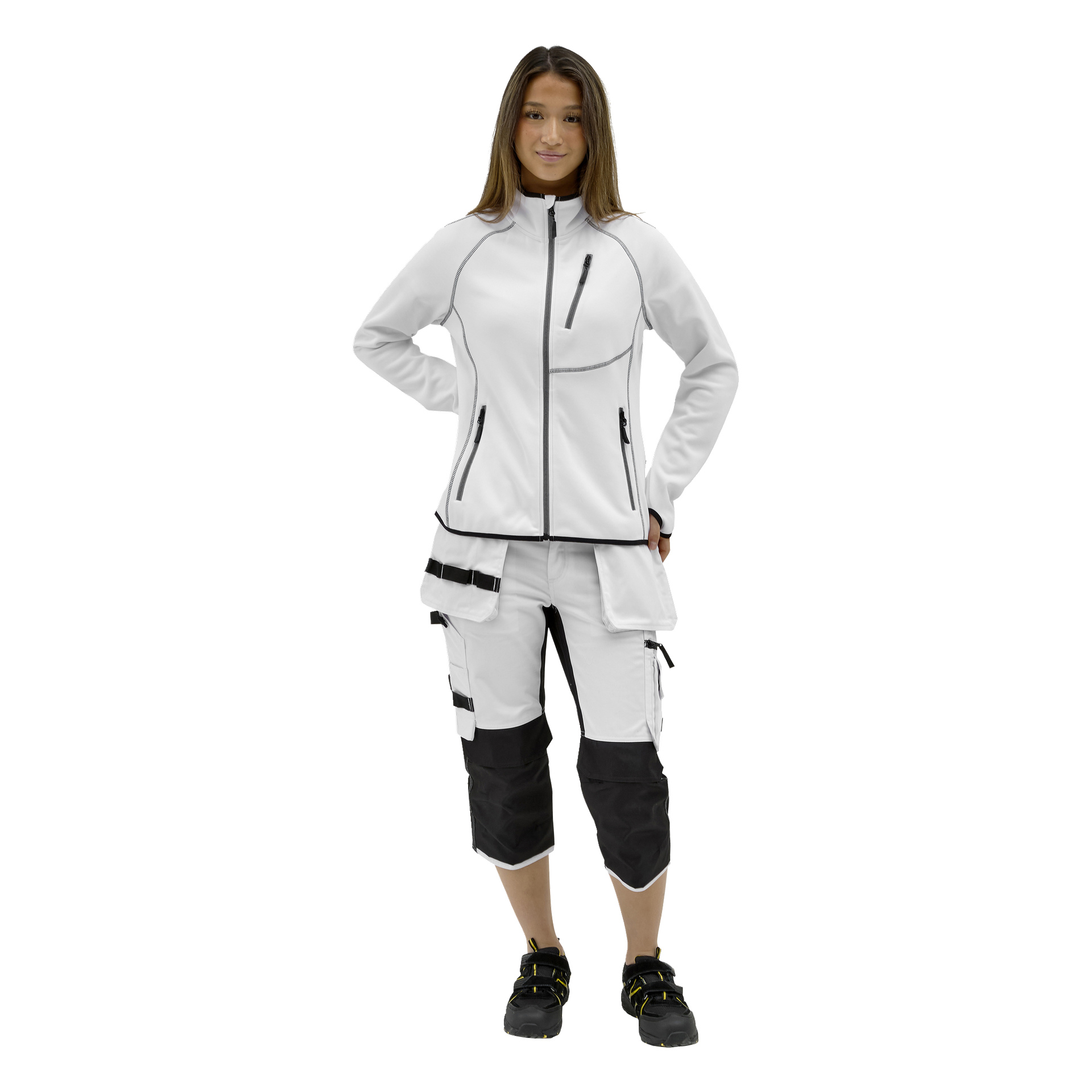 En person står framåt i en vit Bluewear Matilda-tröja med svart kant, vita arbetsbyxor med svarta lappar och svarta skor.