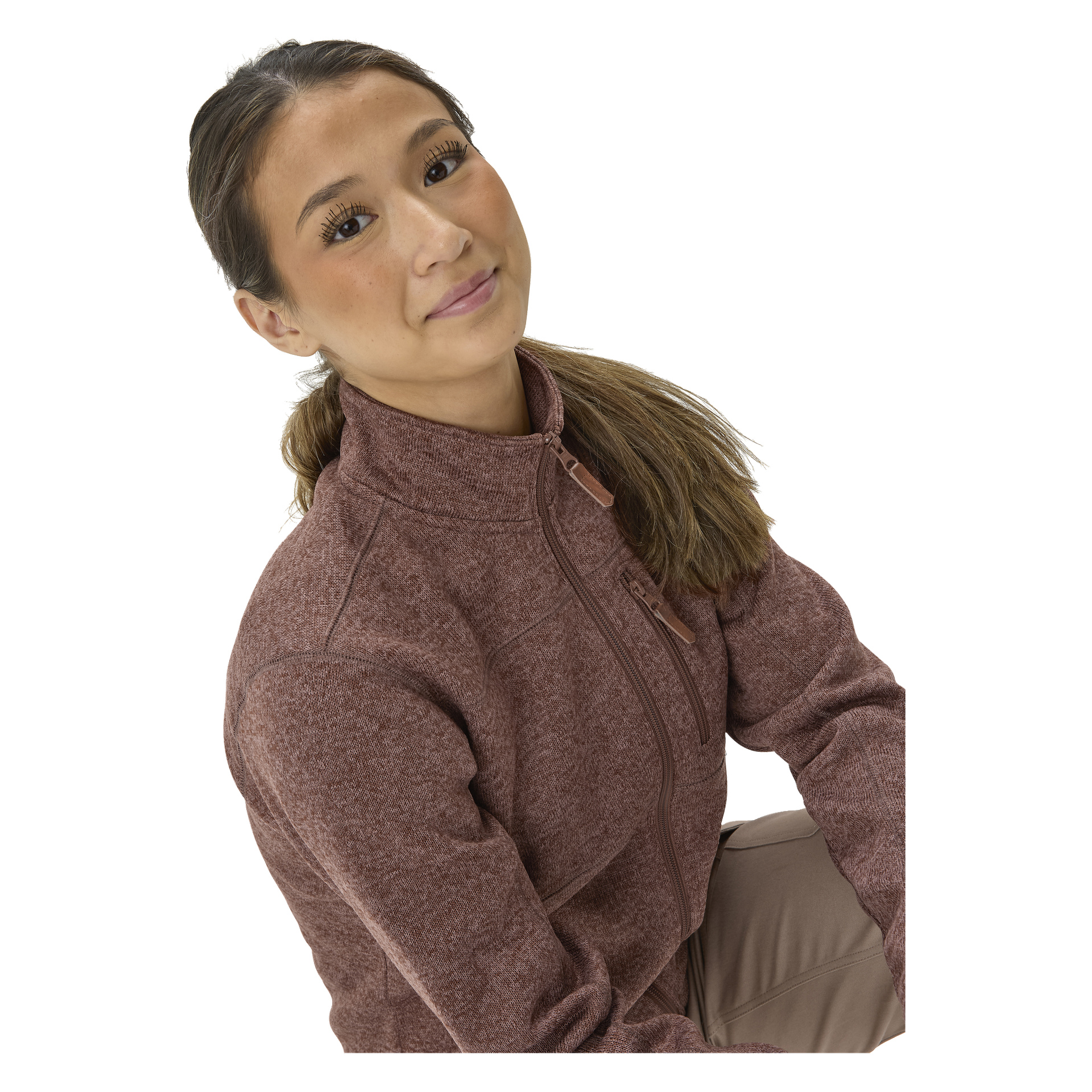 En kvinna med långt brunt hår i hästsvans ler medan hon bär "Kayoba Outdoor Women's knitted fleece sweater MALÅ" och beige byxor.