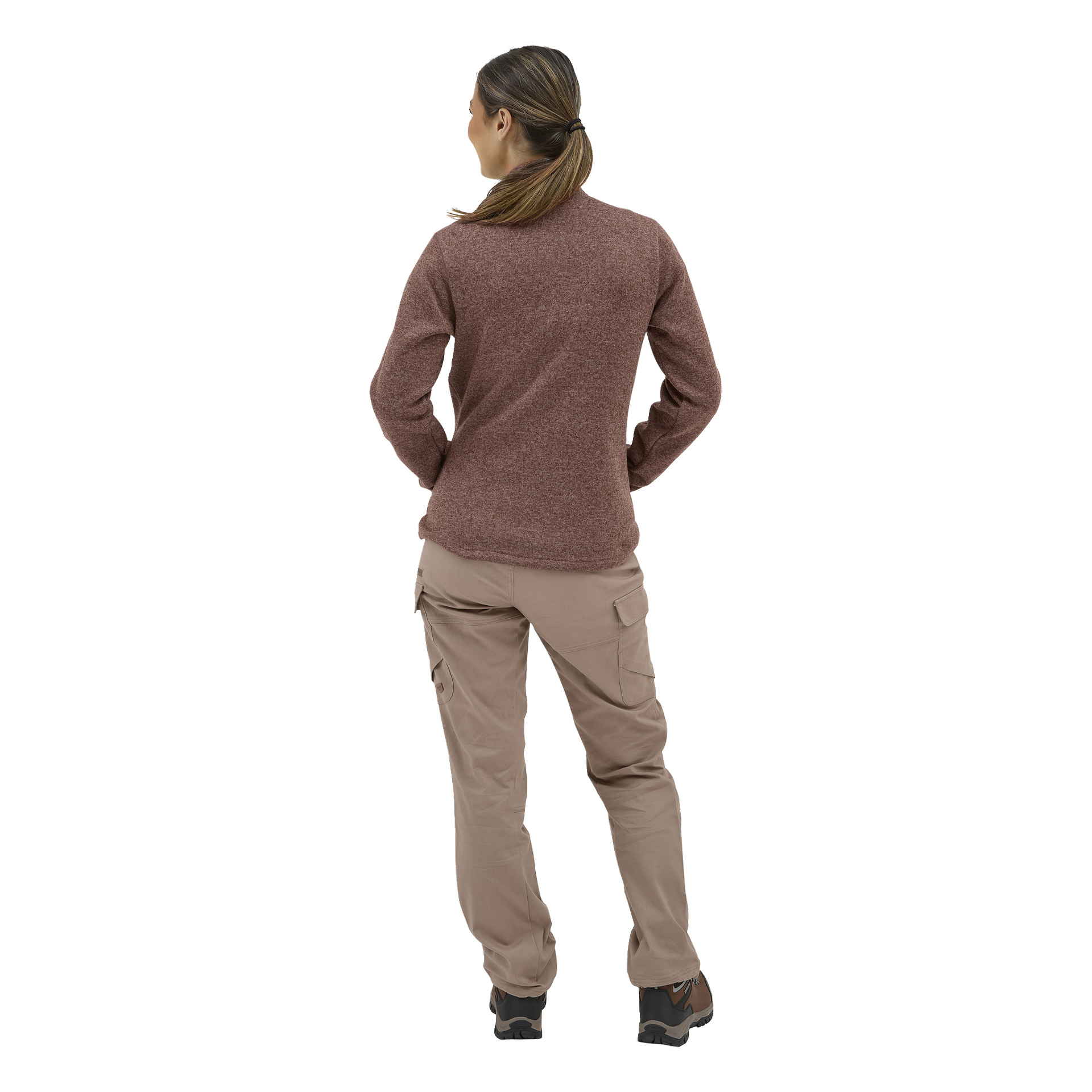 En person med hestehale vender ryggen til, kledd i en burgunder langermet topp, brune tursko og beige Kayoba Outdoor damebukser.