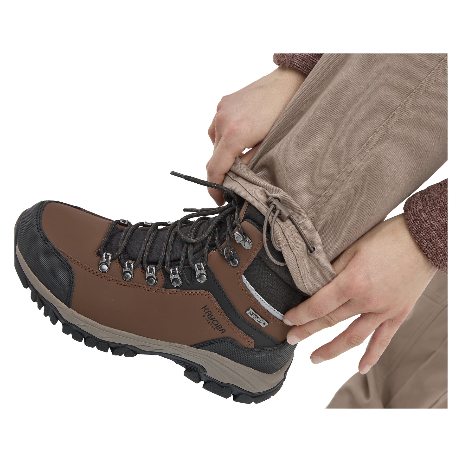 Noen i Kayoba Outdoor Women's Åsen-bukser justerer mansjetten, og viser en brun KROON tursko med robuste lisser og såle.