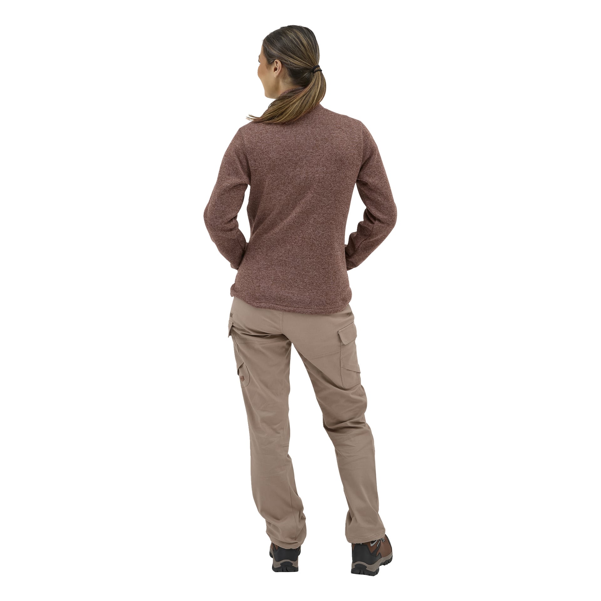 En kvinne vender ryggen til, iført beige Kayoba Outdoor Åsen-bukser, en brun langermet topp, mørke tursko og hestehale.