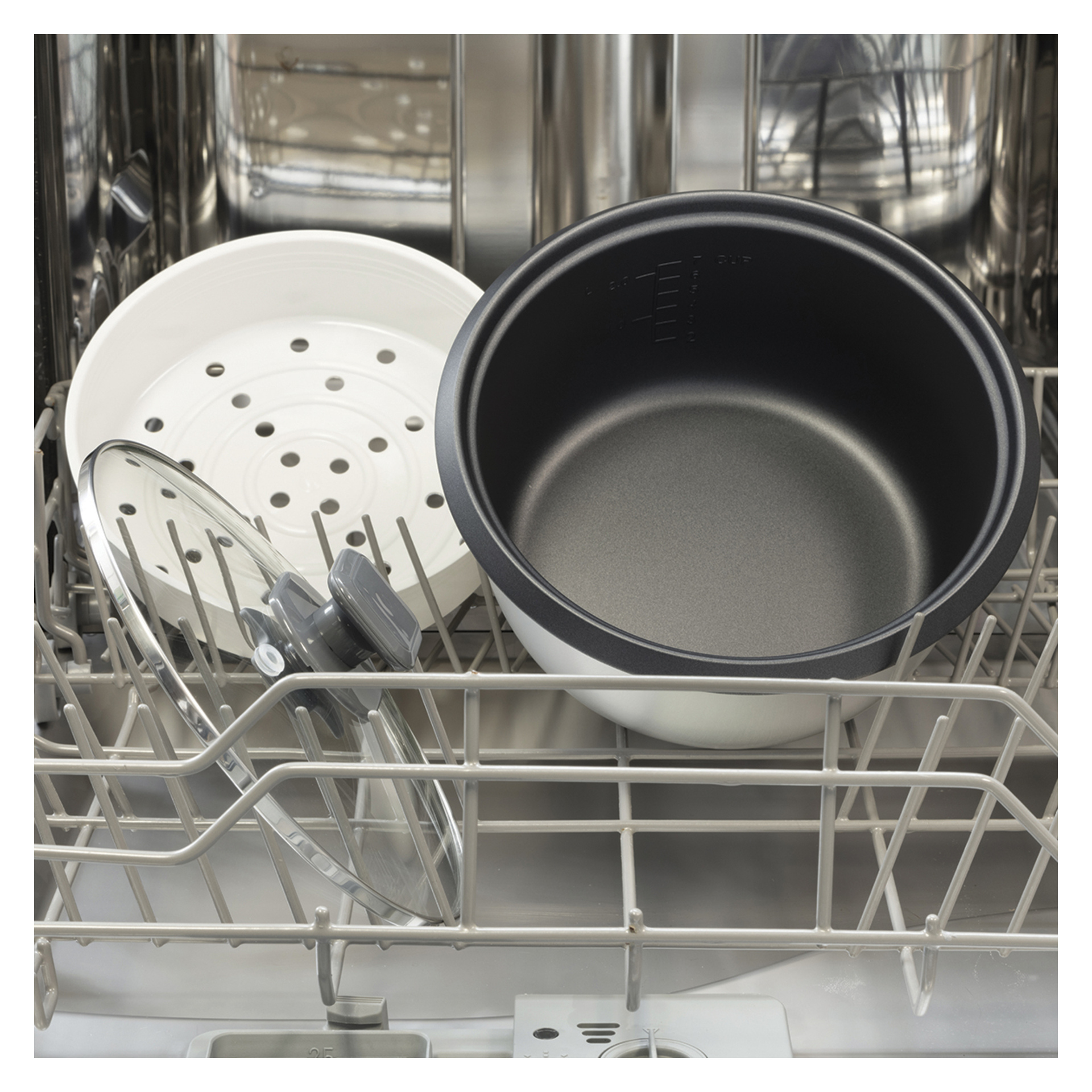 Metalowy garnek, biała taca do parowania i szklana pokrywa Russell Hobbs Rice Cooker Large stoją na dolnej półce zmywarki.