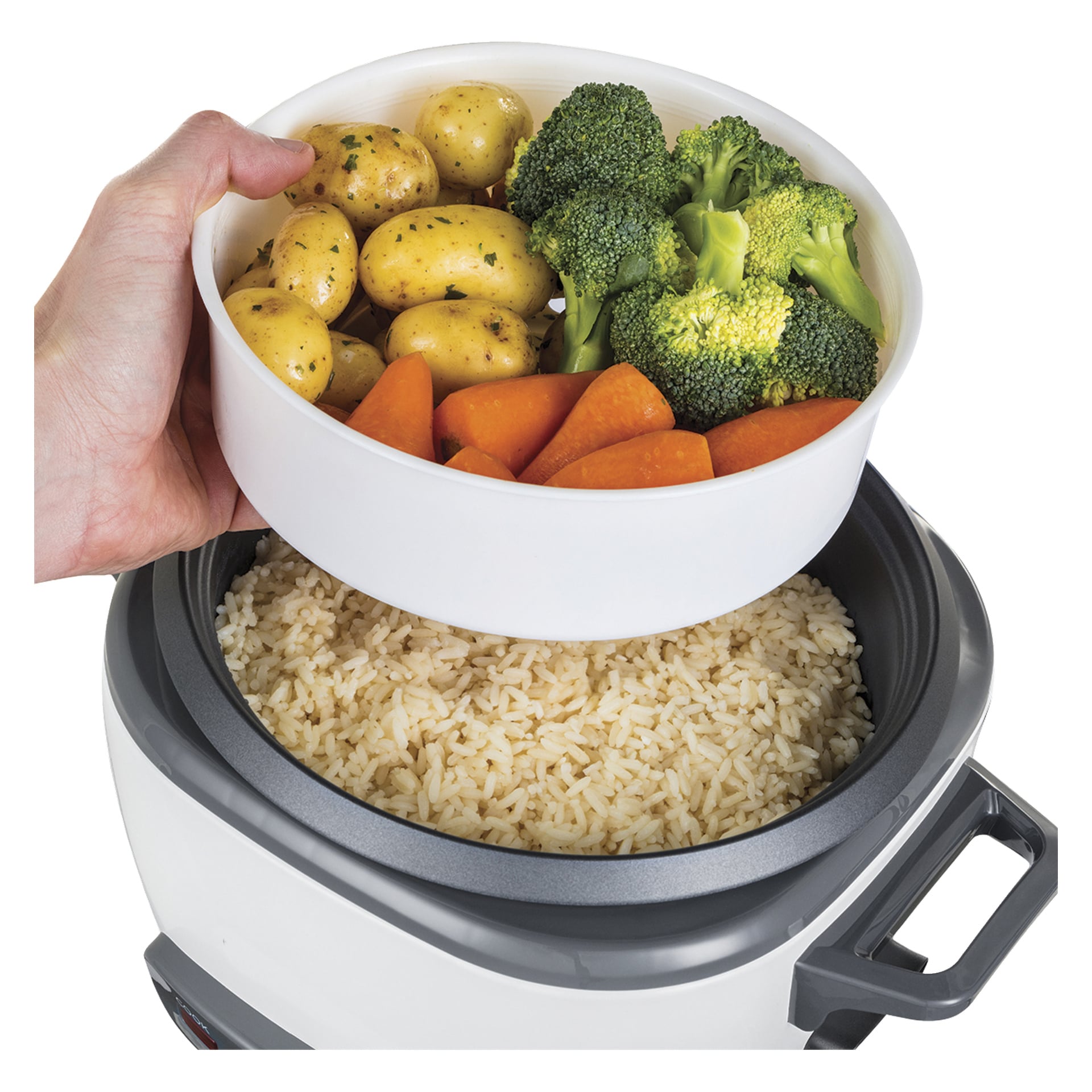 Ręka trzyma parującą tacę z ziemniakami, brokułami i marchewkami nad szarym i białym ryżowarem Russell Hobbs wypełnionym ryżem.